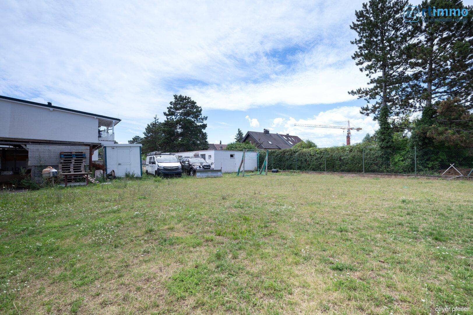 Große Rasenfläche im Garten mit Blick auf das Haus und einige Fahrzeuge.
