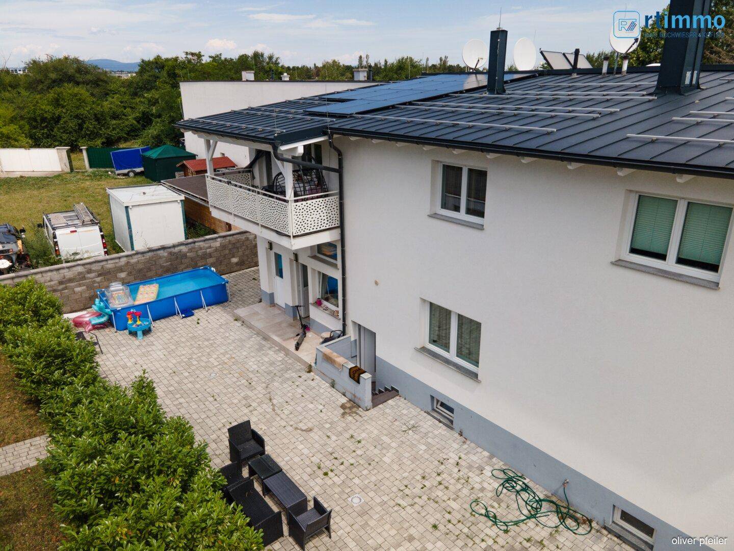 Luftaufnahme des Hauses mit gepflastertem Hof, Pool und Solaranlage auf dem Dach.