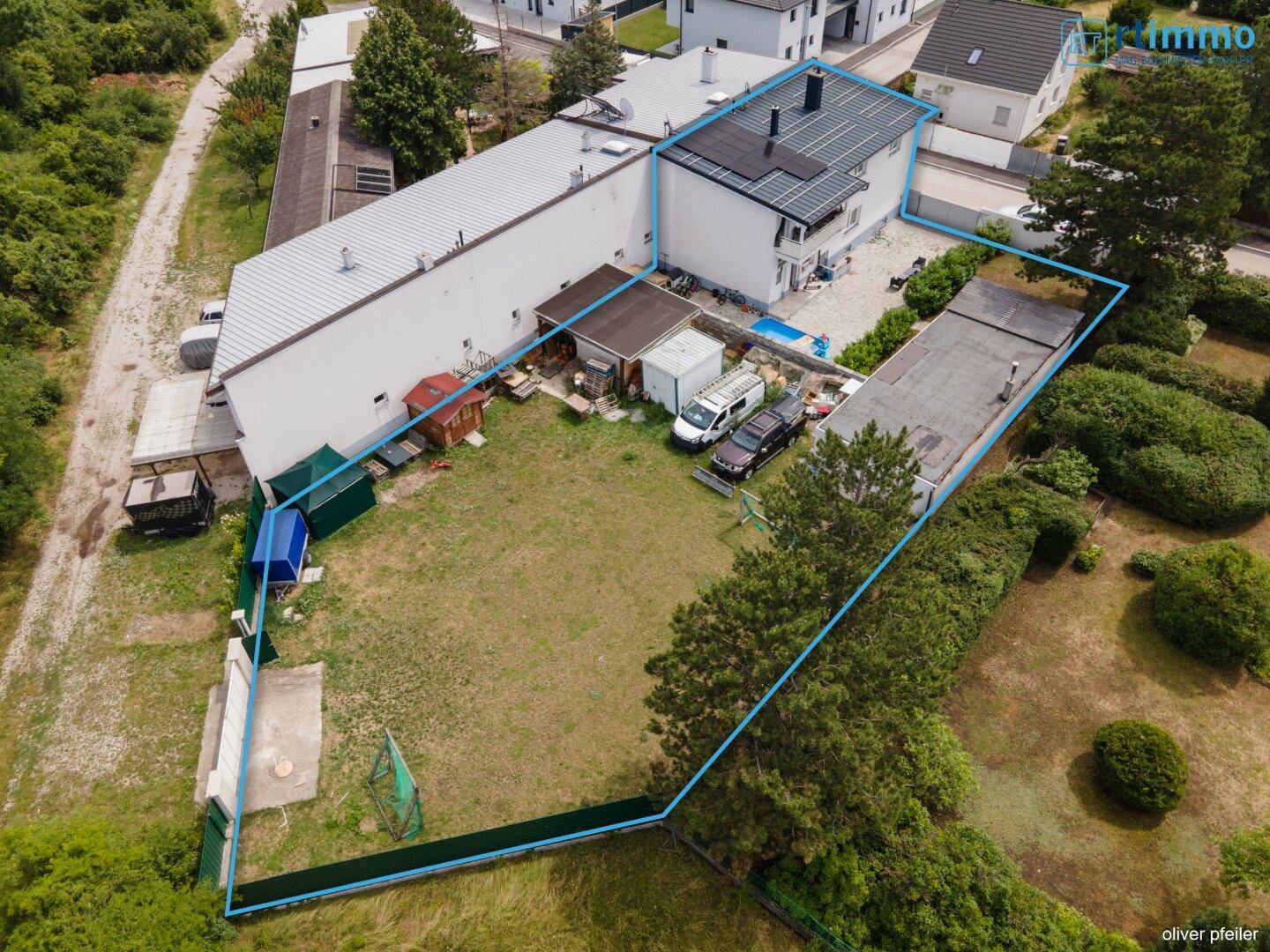 Luftaufnahme des Grundstücks mit blauem Umriss, zeigt das Haus, Garten und Nebengebäude.