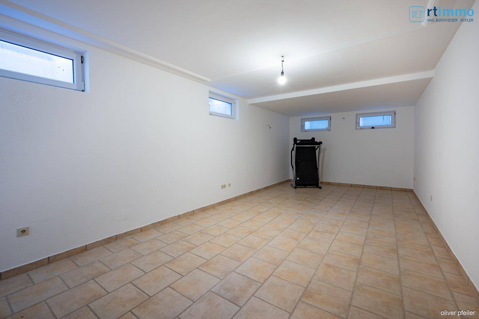 Geräumiger Kellerraum mit Fliesenboden und kleinen Fenstern, die Tageslicht hereinlassen.