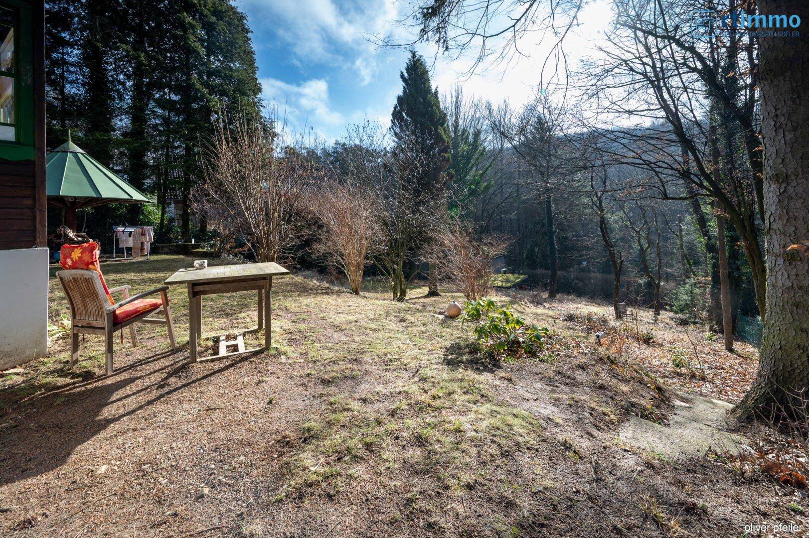 Weitläufiger Gartenbereich mit Sitzgelegenheiten und freiem Blick auf die umliegende Natur und Wälder.
