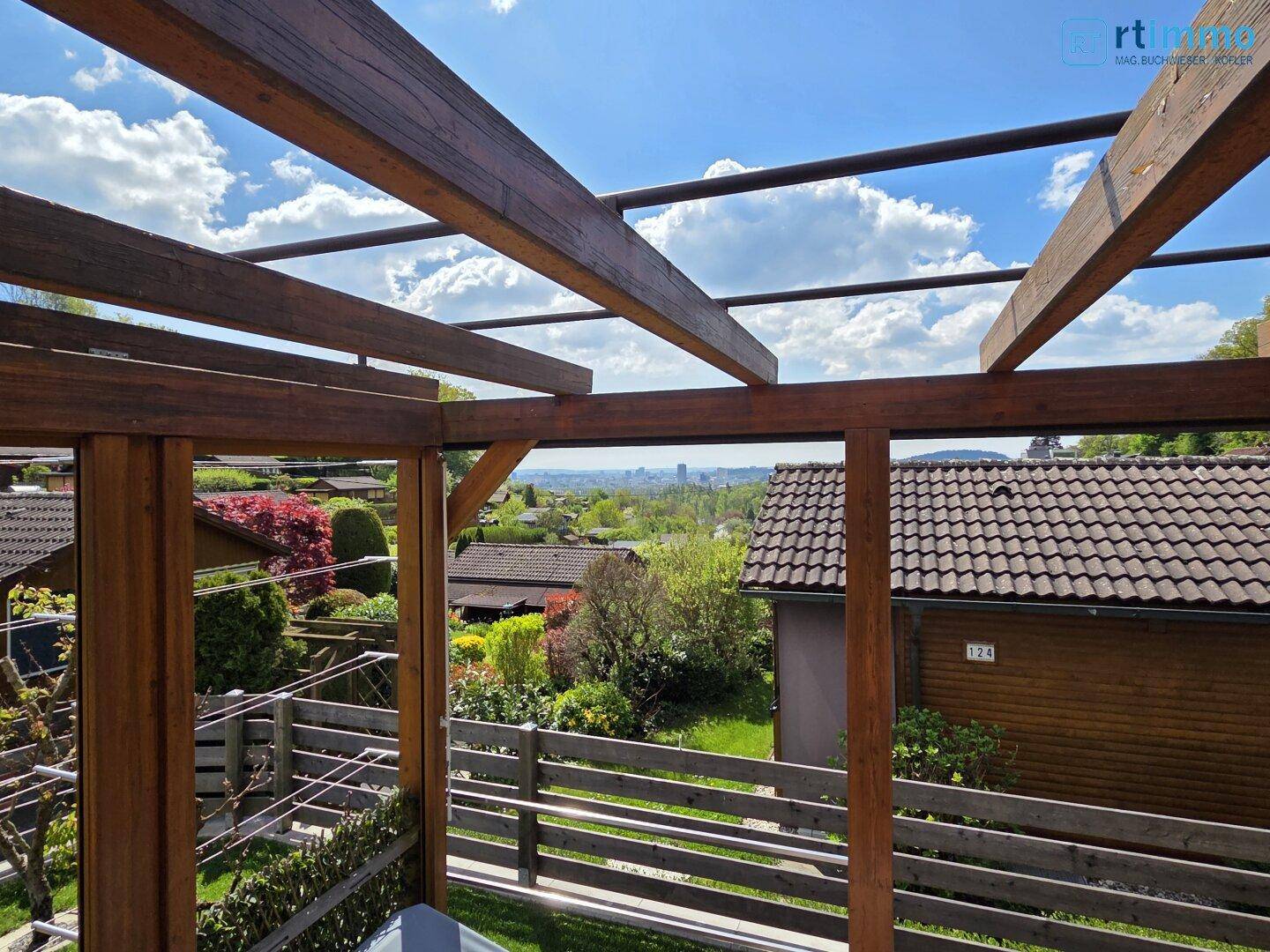 Überdachte Terrasse mit Holzpergola und weitem Blick über die Dächer und die Stadtlandschaft.