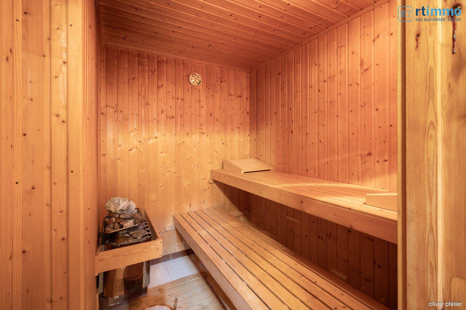 Traditionelle Holzsauna mit mehreren Bänken und einem Saunaofen für entspannende Momente.