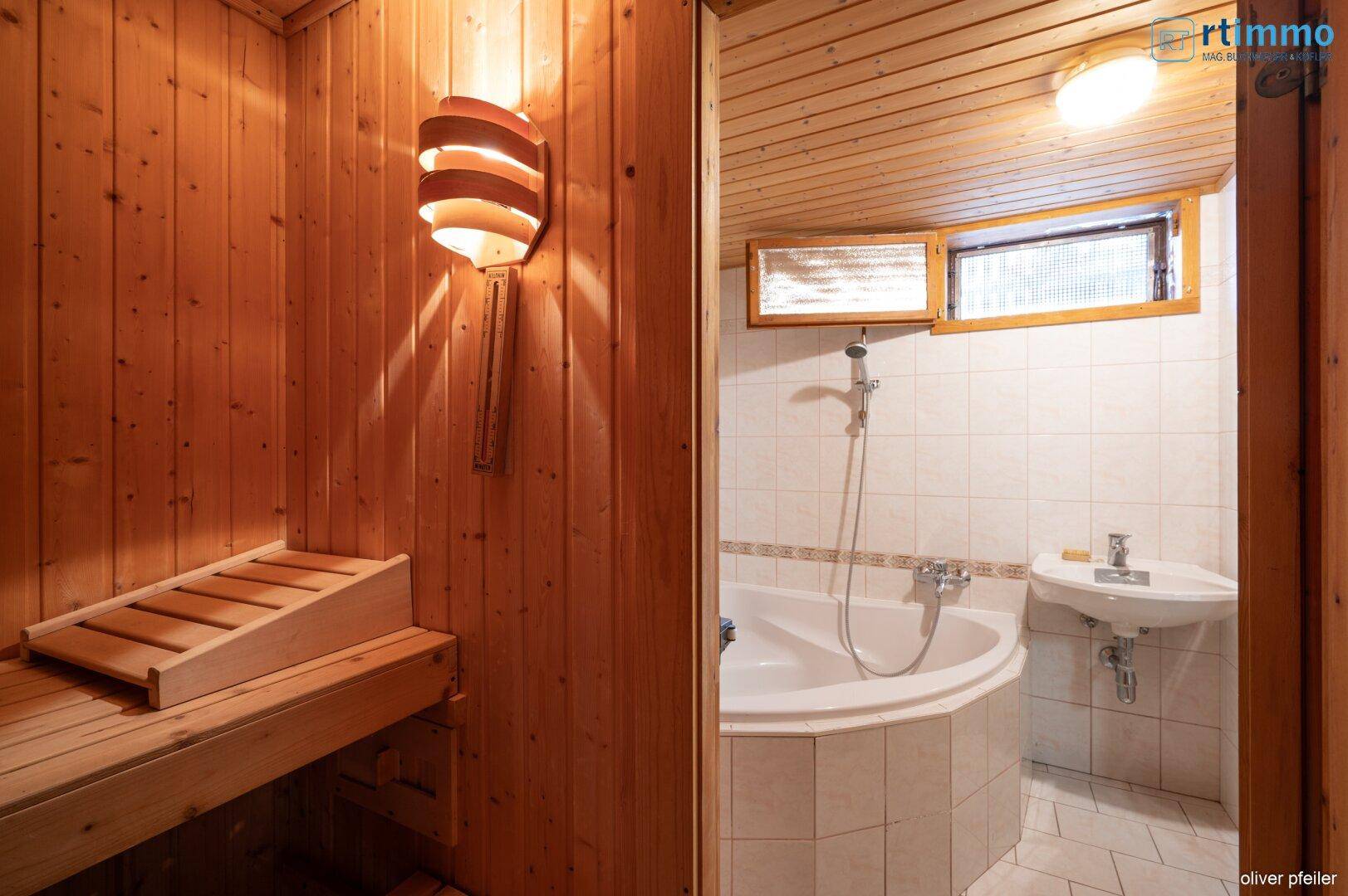 Badezimmer mit Eckbadewanne und kleinem Waschbecken, direkt neben dem Saunabereich gelegen.