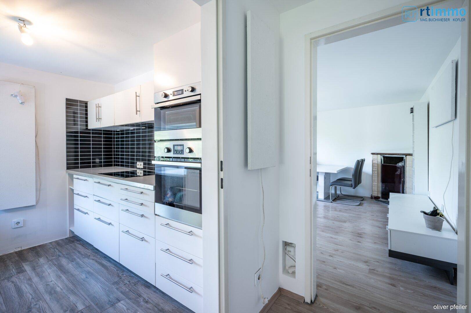 Moderne Küche mit weißen Fronten und Blick in den angrenzenden Essbereich.