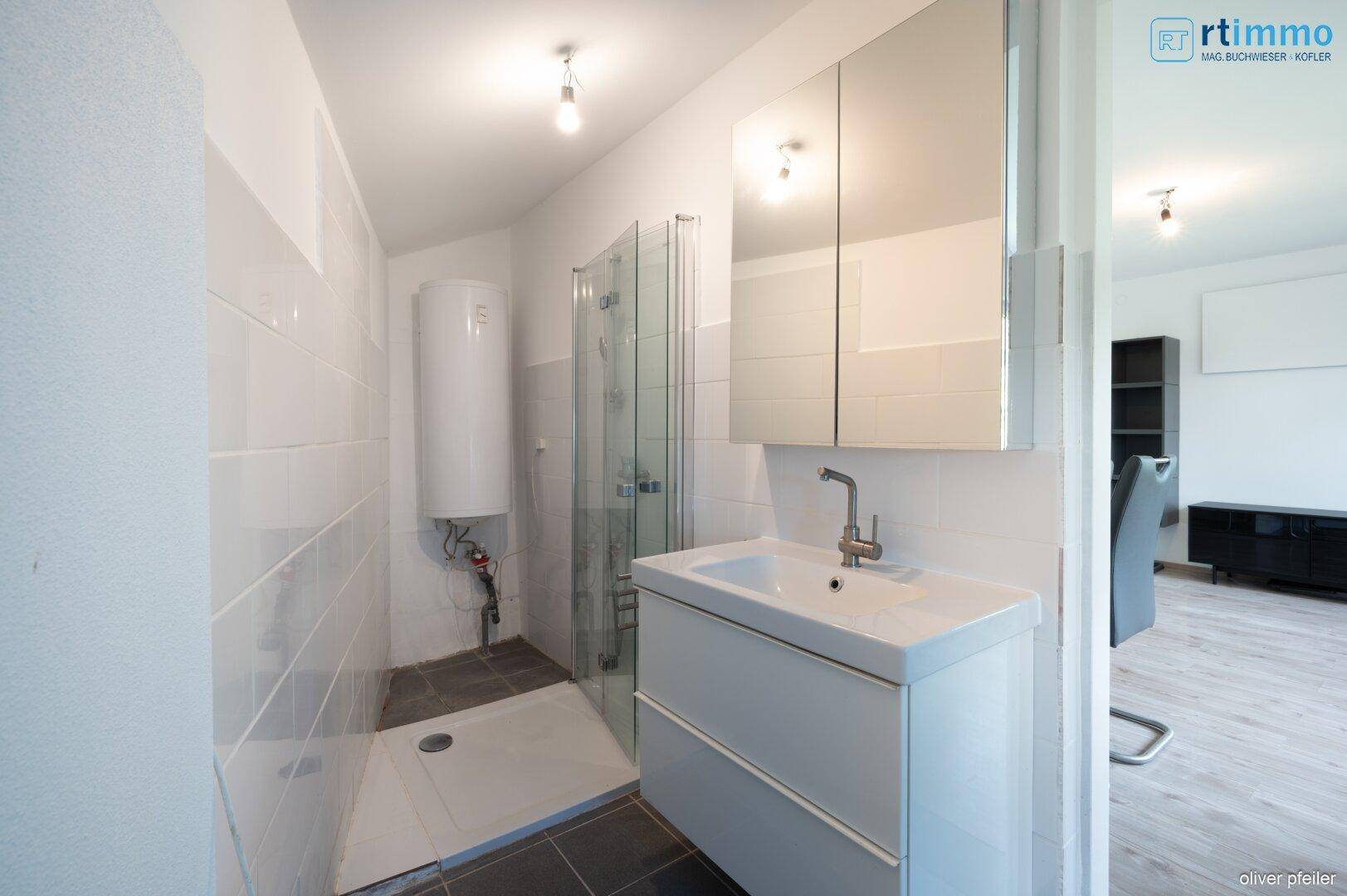 Modernes Badezimmer mit Dusche, Waschbecken und Spiegelschrank in hellen Farben.