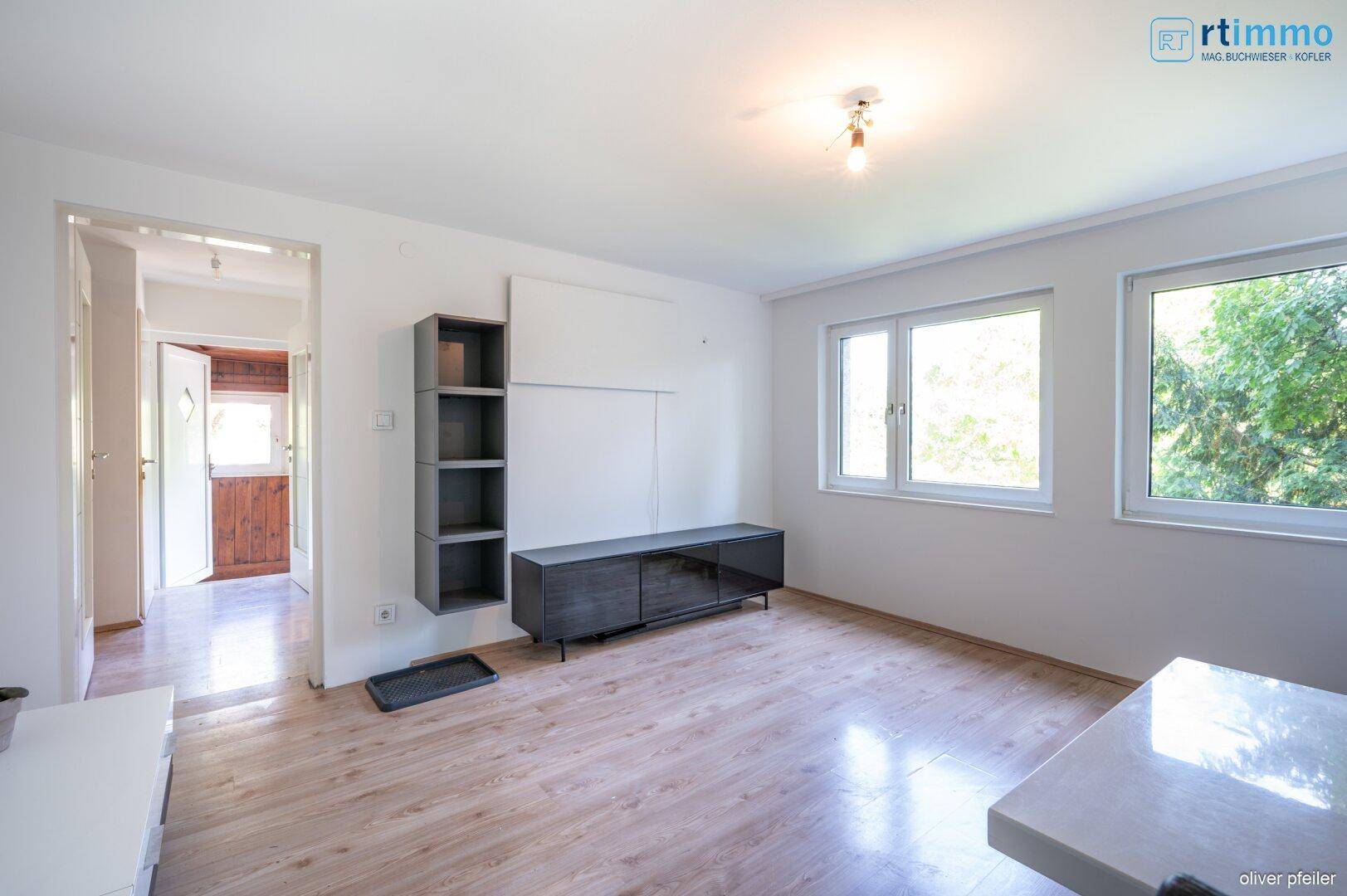 Helles Wohnzimmer mit Laminatboden, modernen Möbeln und Blick ins Grüne.