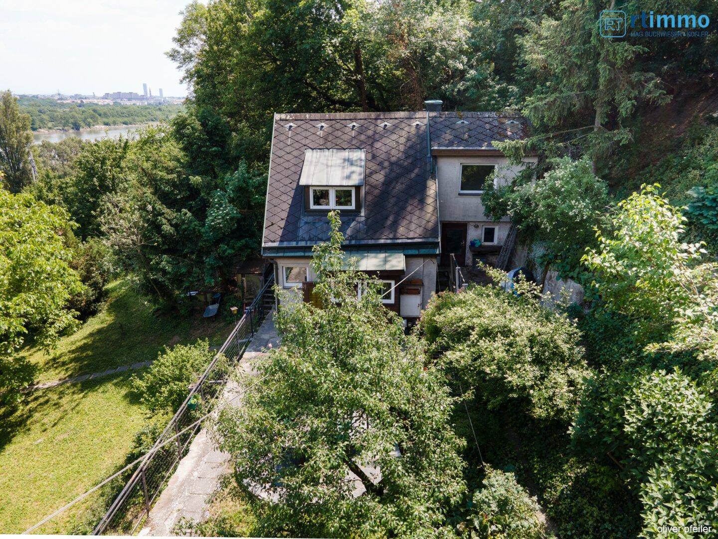 Luftaufnahme eines Hauses umgeben von viel Grün mit Fluss im Hintergrund.