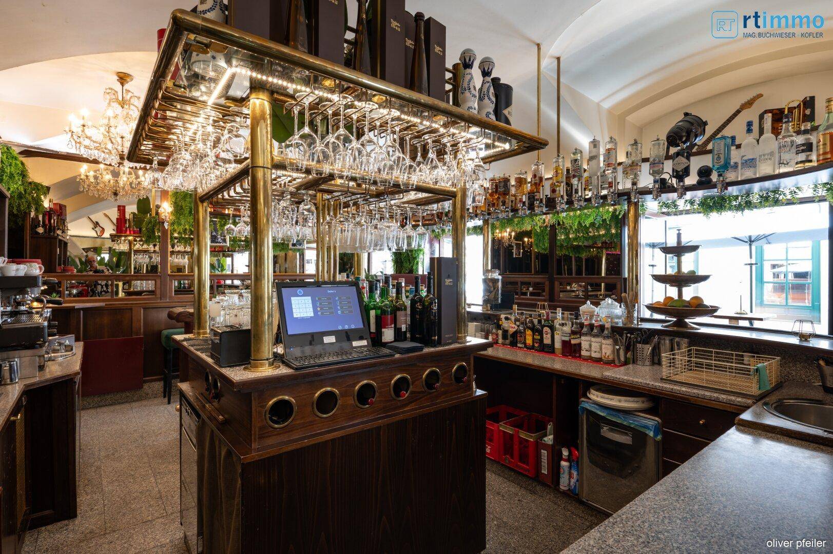 Der Arbeitsbereich der Bar mit Kasse, Gläsern und Flaschen, umgeben von dunklem Holz.