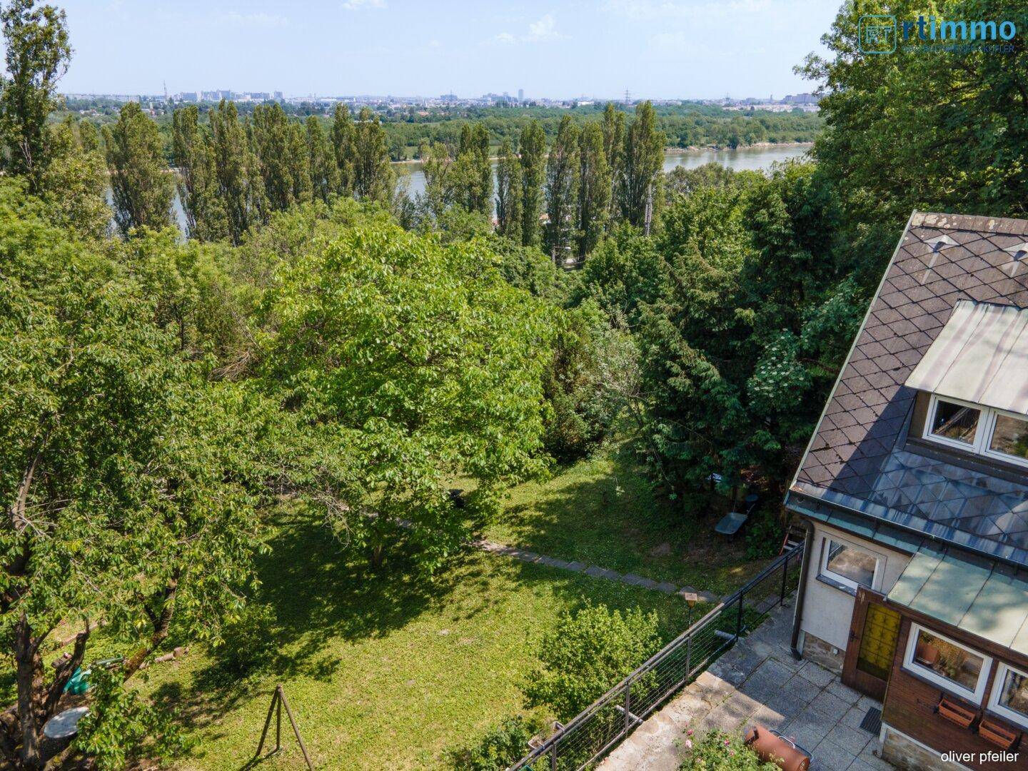 Luftaufnahme des Hauses mit weitem Blick über die Baumwipfel bis zum Fluss und der Stadt.