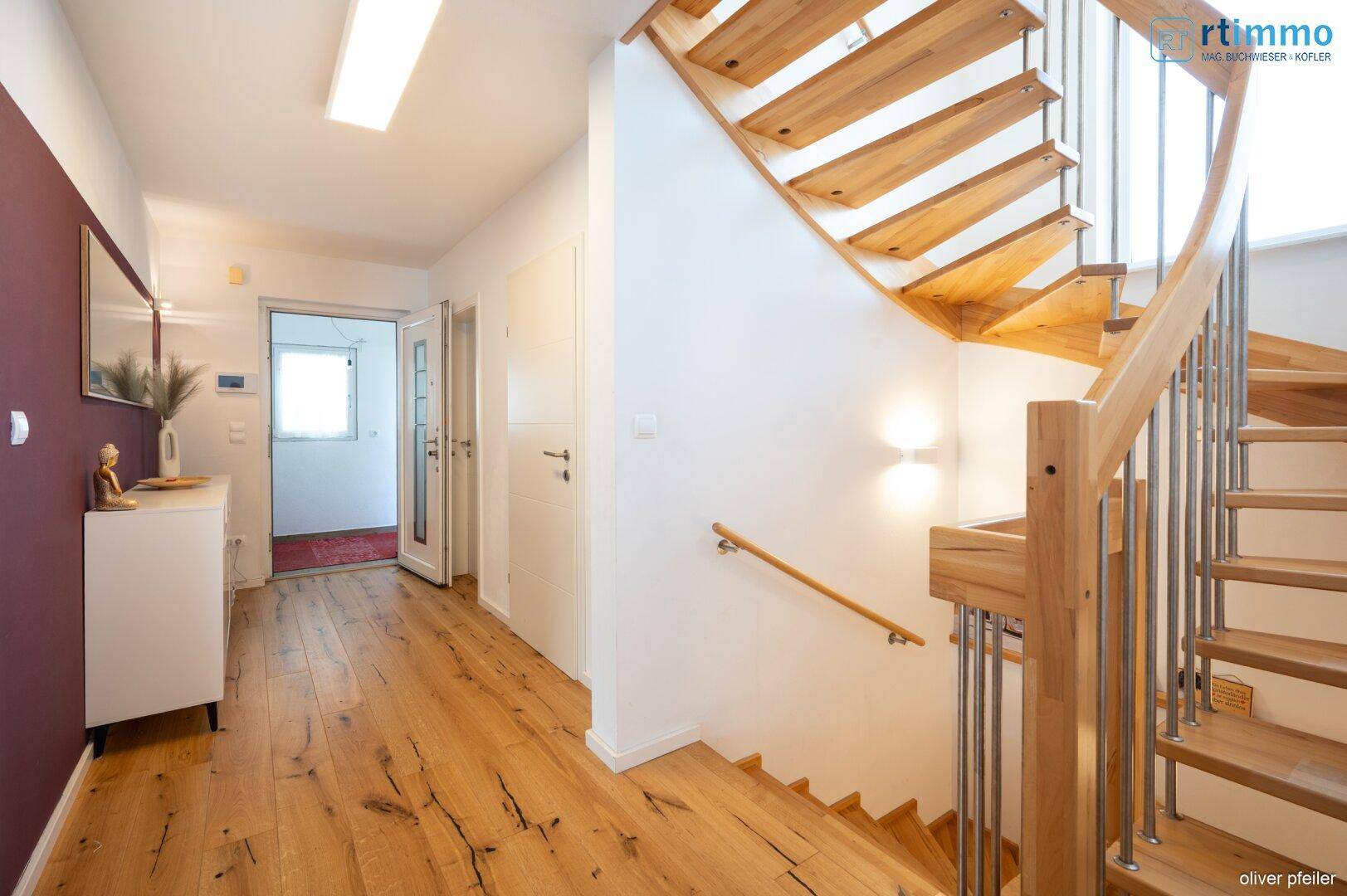 Heller Flur mit eleganter Holztreppe und Holzboden, der die oberen Etagen verbindet.