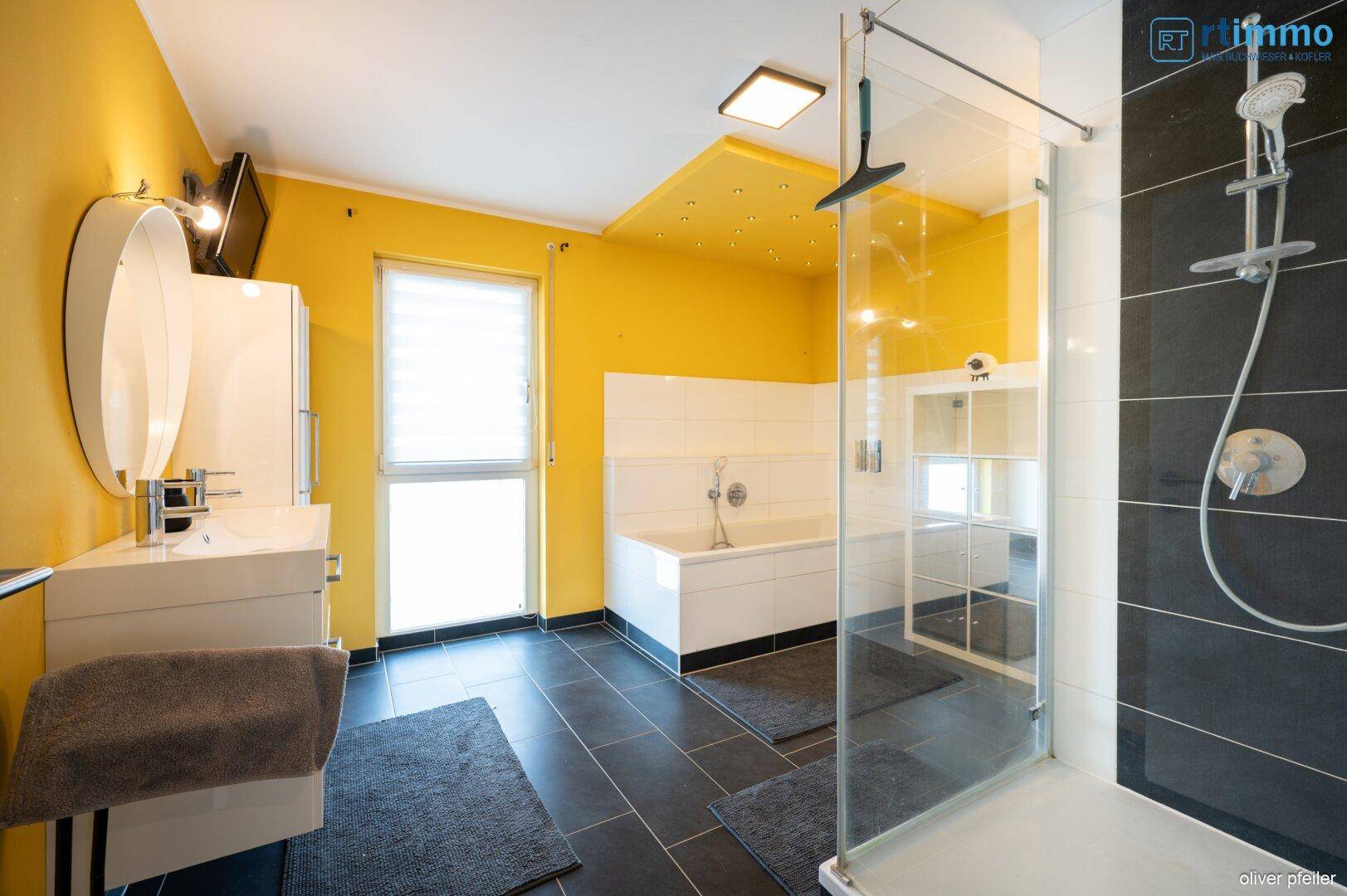 Modernes Badezimmer mit gelben Wänden, Doppelwaschbecken, großer Dusche und Badewanne.