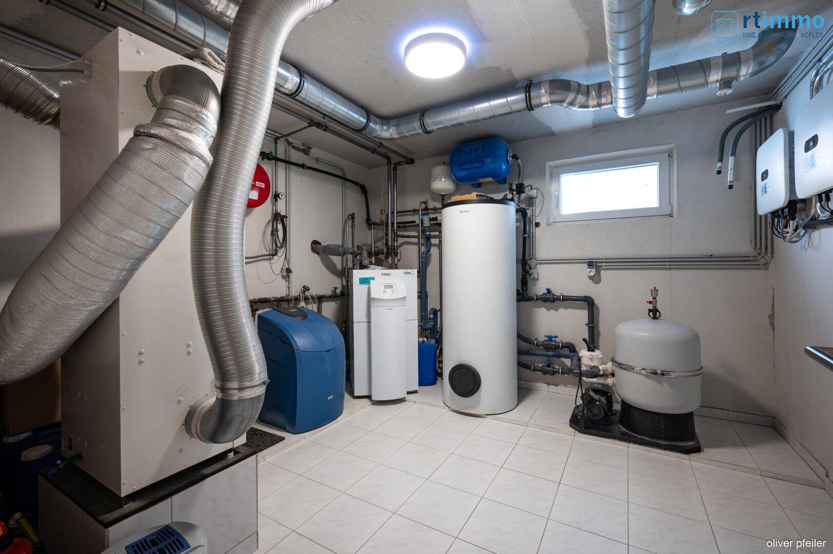Technikraum im Keller mit Heizungsanlage, Warmwasserspeicher und Lüftungssystem.