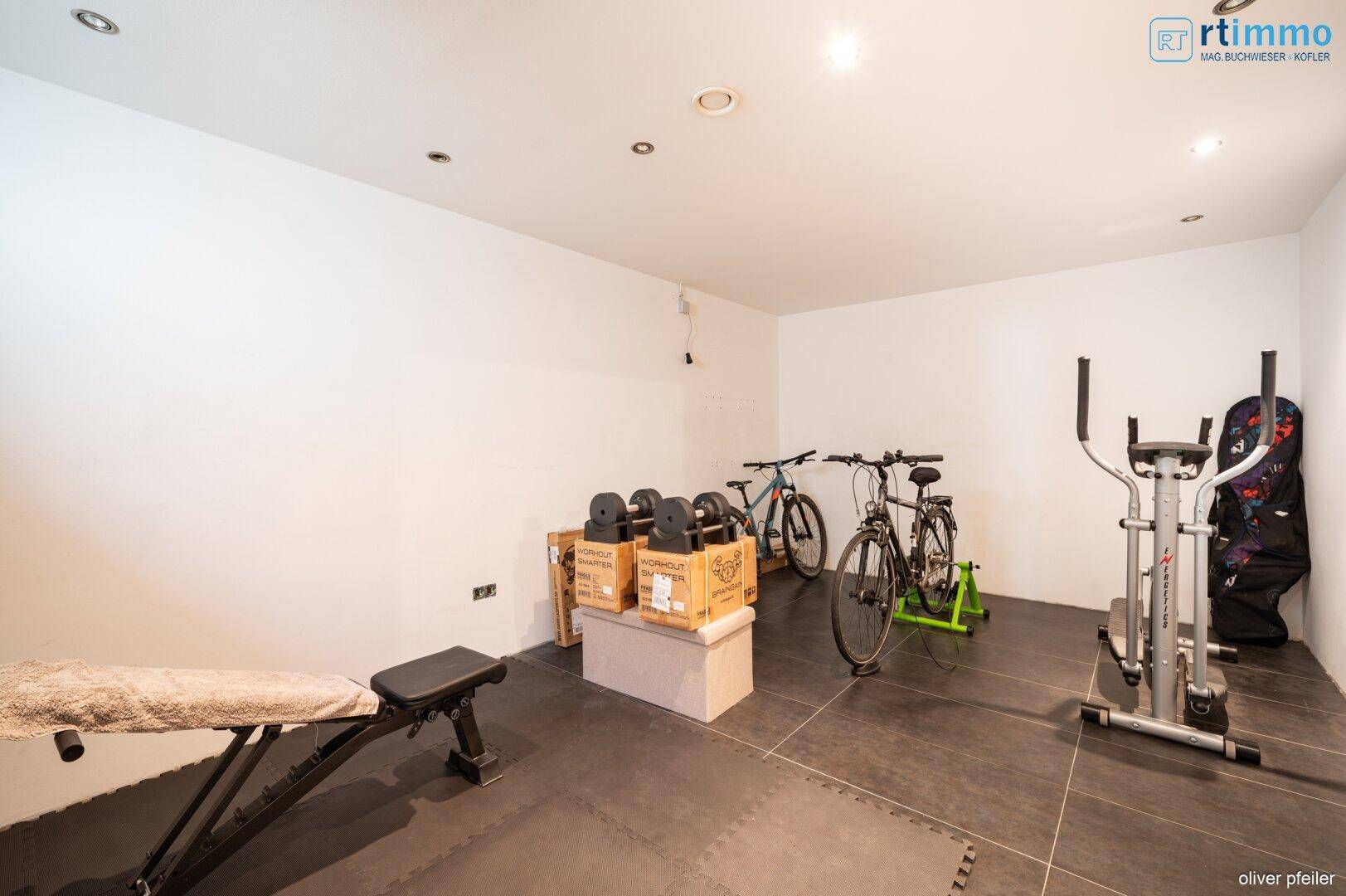 Fitnessraum im Keller mit Sportgeräten und Fahrrädern, ideal für das Training zu Hause.