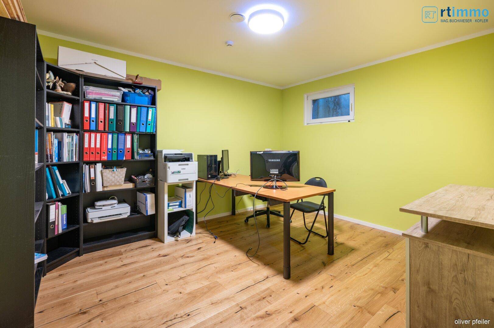 Helles Heimbüro im Keller mit grün gestrichenen Wänden und Holzboden.