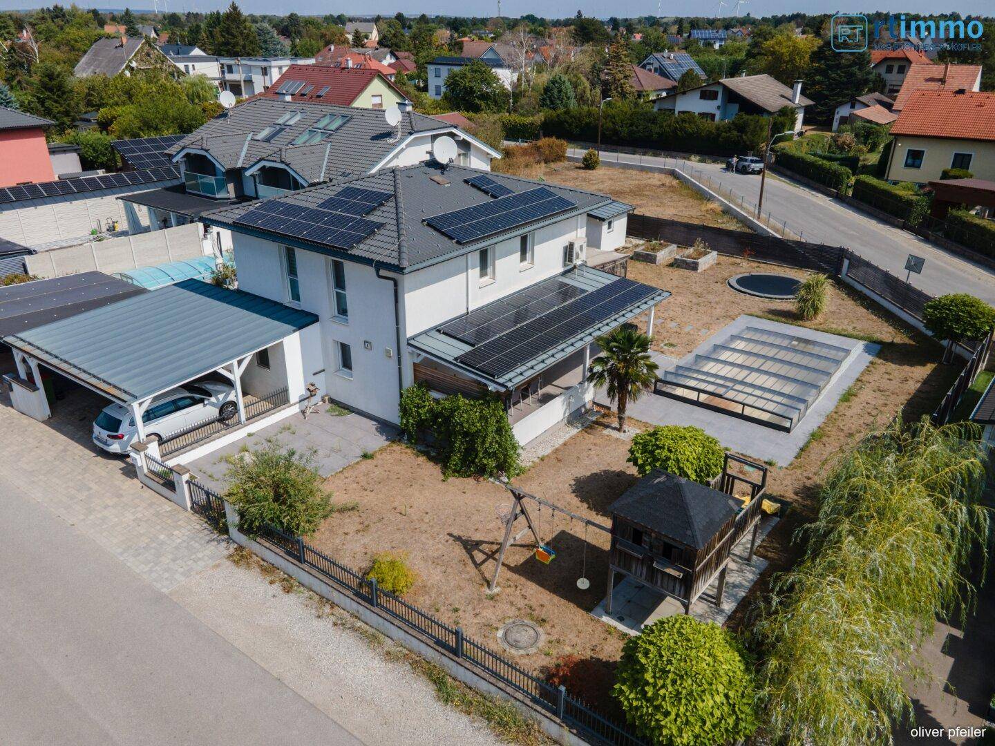 Luftaufnahme des Hauses mit großem Garten, Carport und Photovoltaikanlage auf dem Dach.