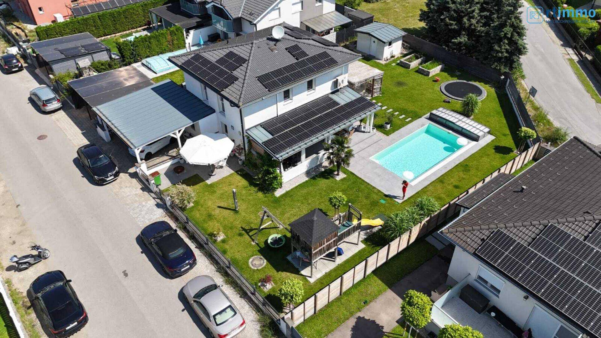 Übersicht des Anwesens von oben mit Pool, Garten, Solaranlagen und angrenzender Straße.