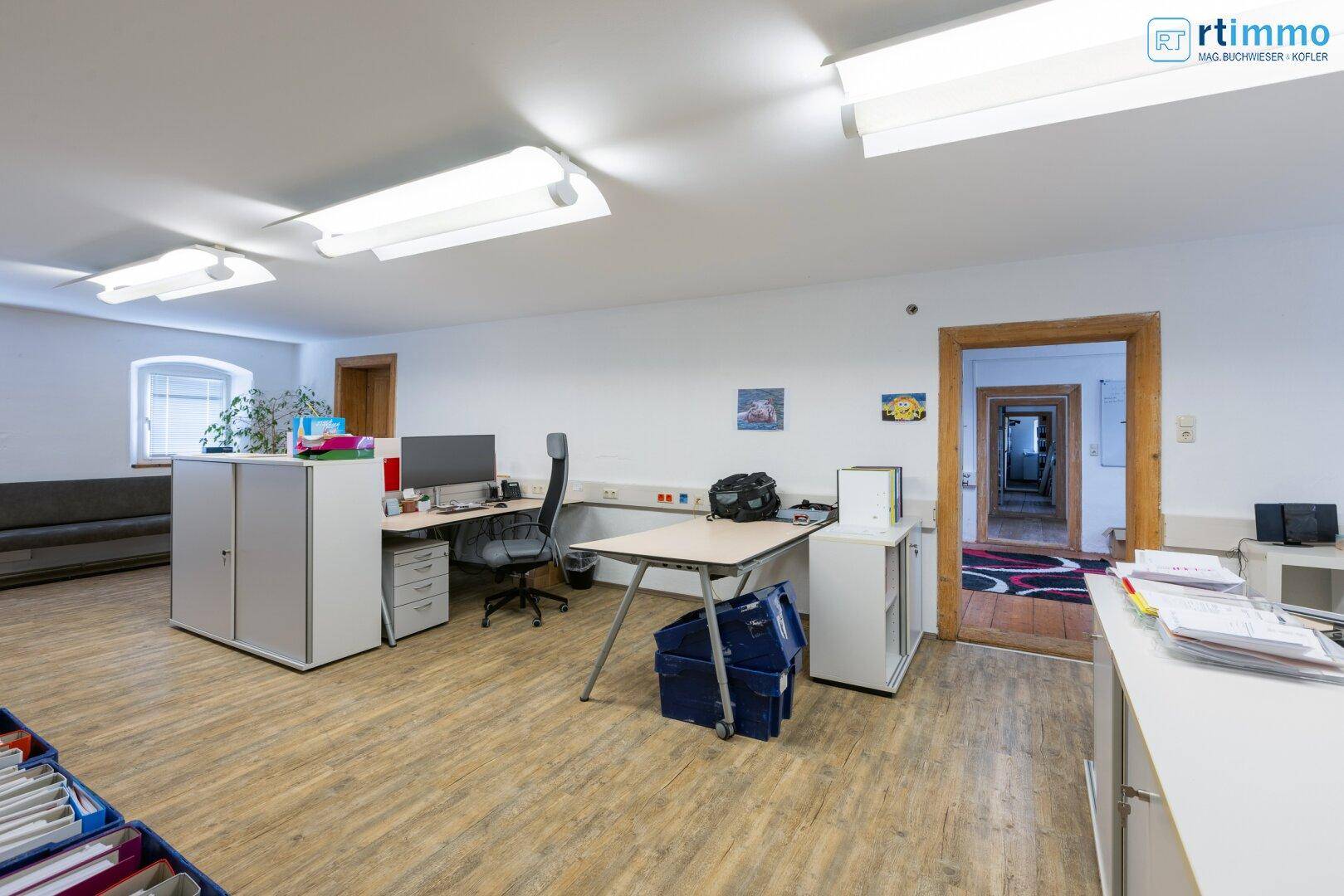 Helles Büro mit mehreren Arbeitsplätzen, Holzfußboden und funktionaler Einrichtung.