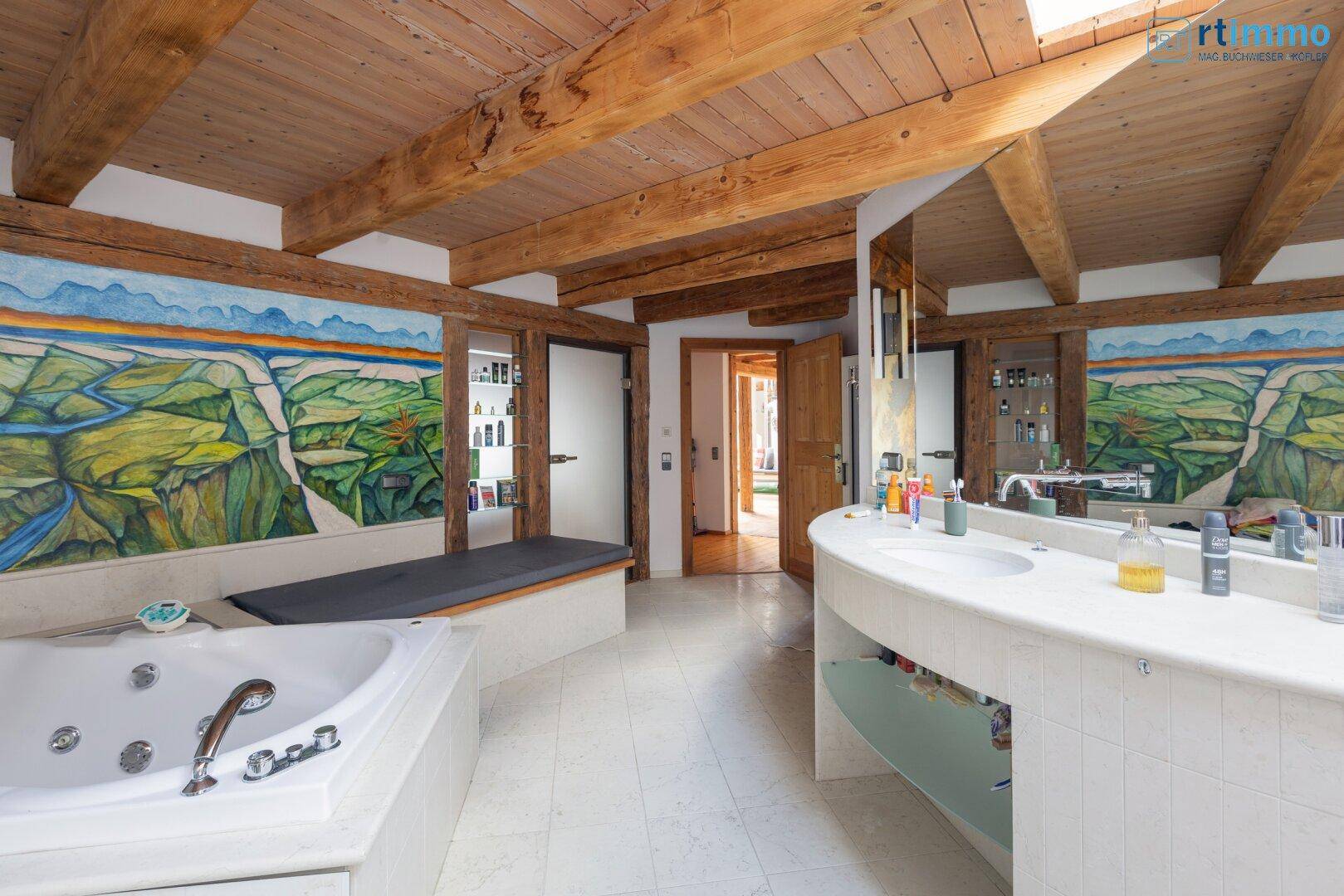 Geräumiges Badezimmer mit Doppelwaschbecken, Badewanne und Holzbalken an der Decke.