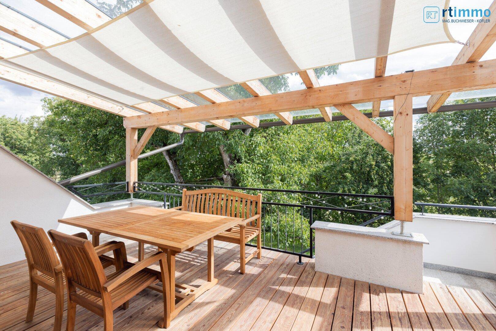 Überdachte Terrasse mit Holzboden, Gartenmöbeln und Blick ins Grüne.