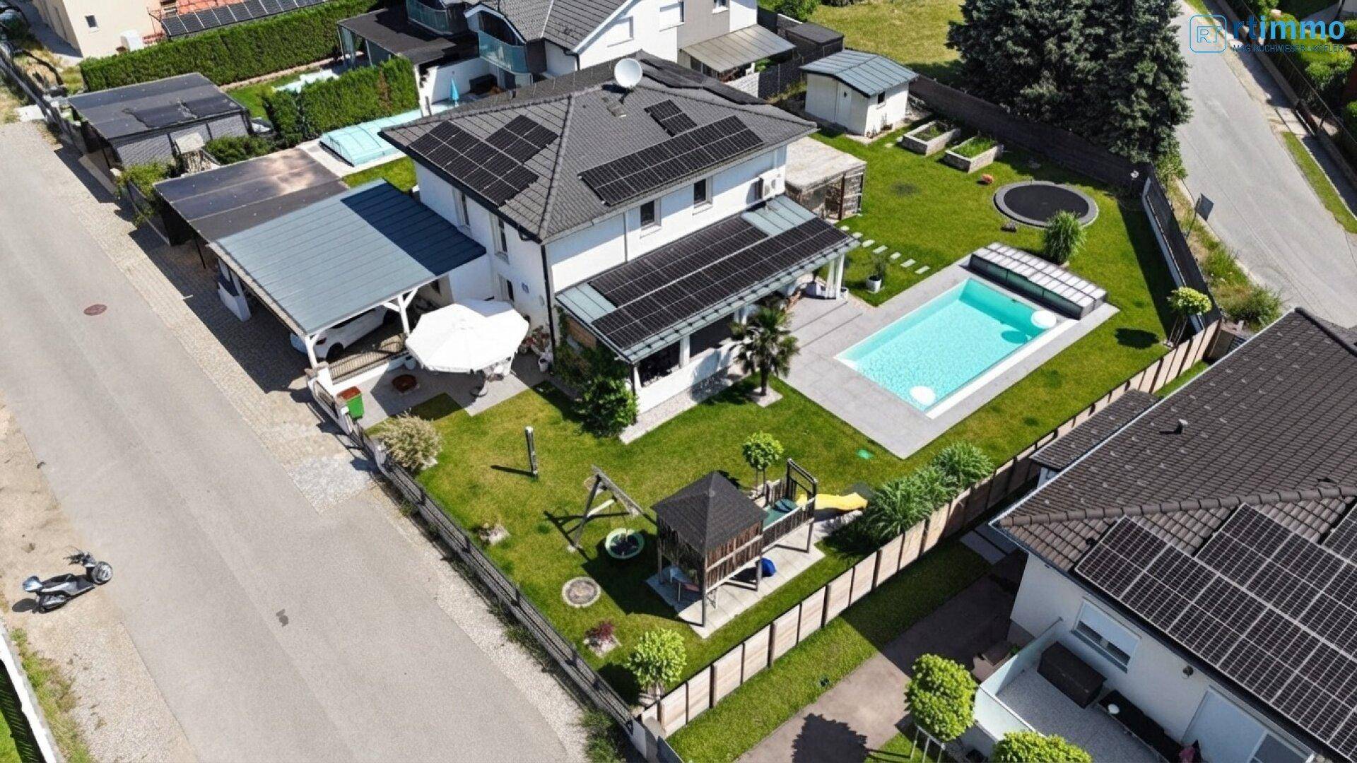 Vogelperspektive des Hauses mit Pool, großem Garten, Kinderspielplatz und Carport.