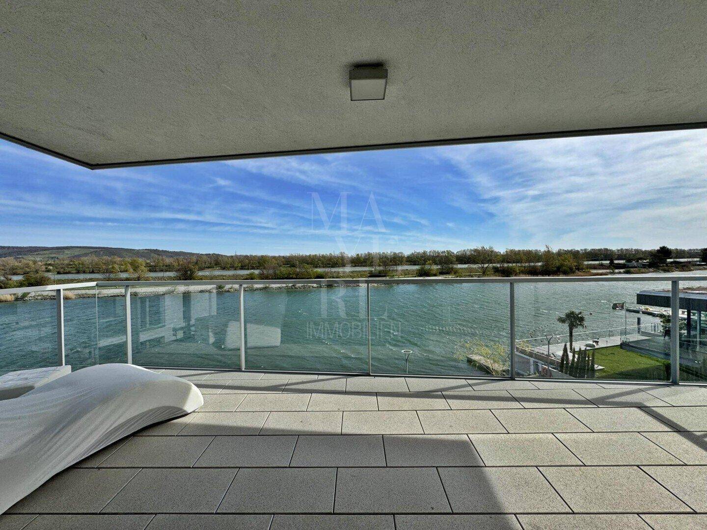 Sonniger Balkon mit bequemer Liege und unverbautem Blick auf den See und die Natur.