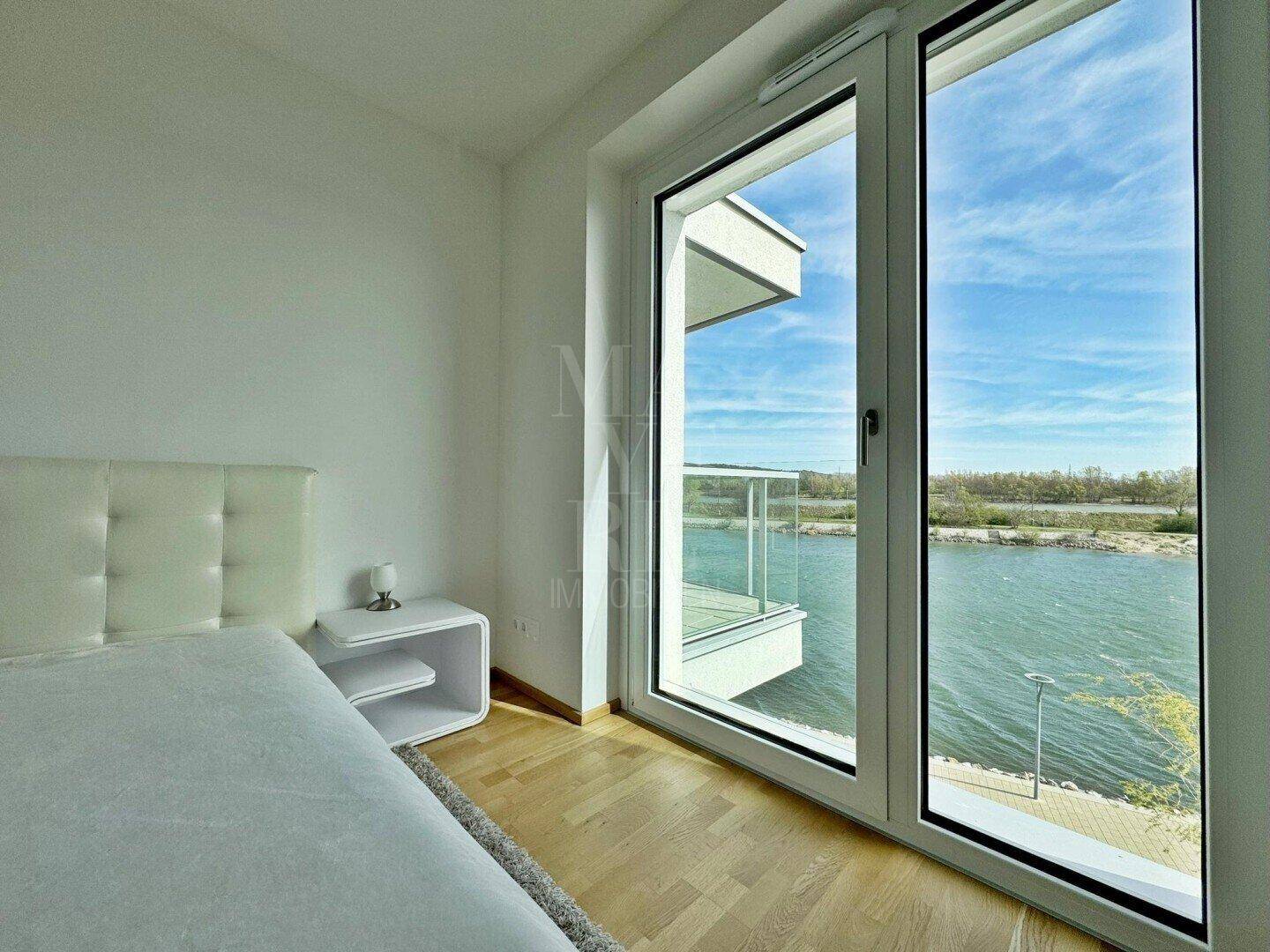 Helles Schlafzimmer mit großen Fenstern, die einen weiten Blick auf den See bieten.