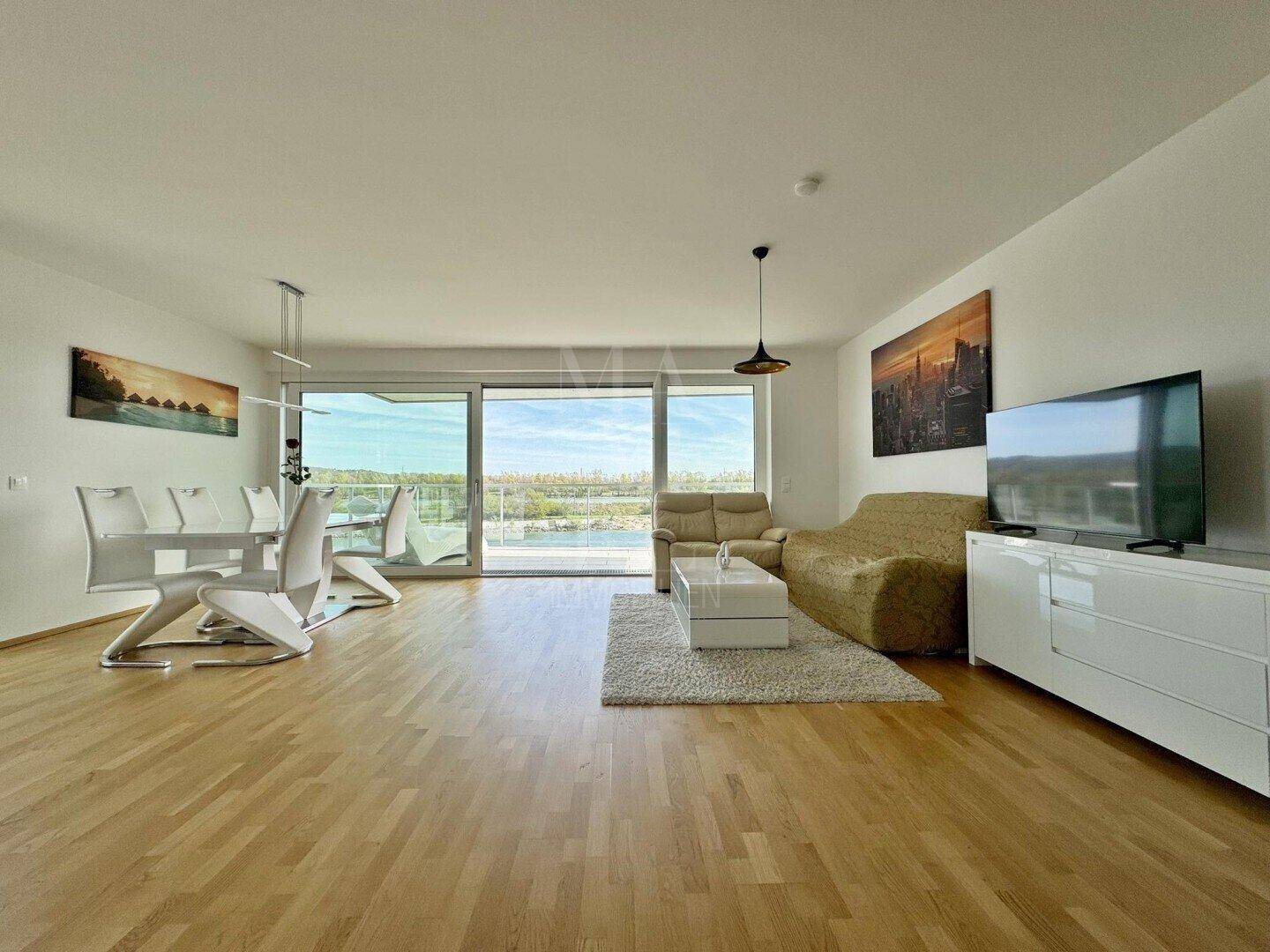 Geräumiger Wohn-Essbereich mit Parkettboden, moderner Einrichtung und Zugang zum Balkon.