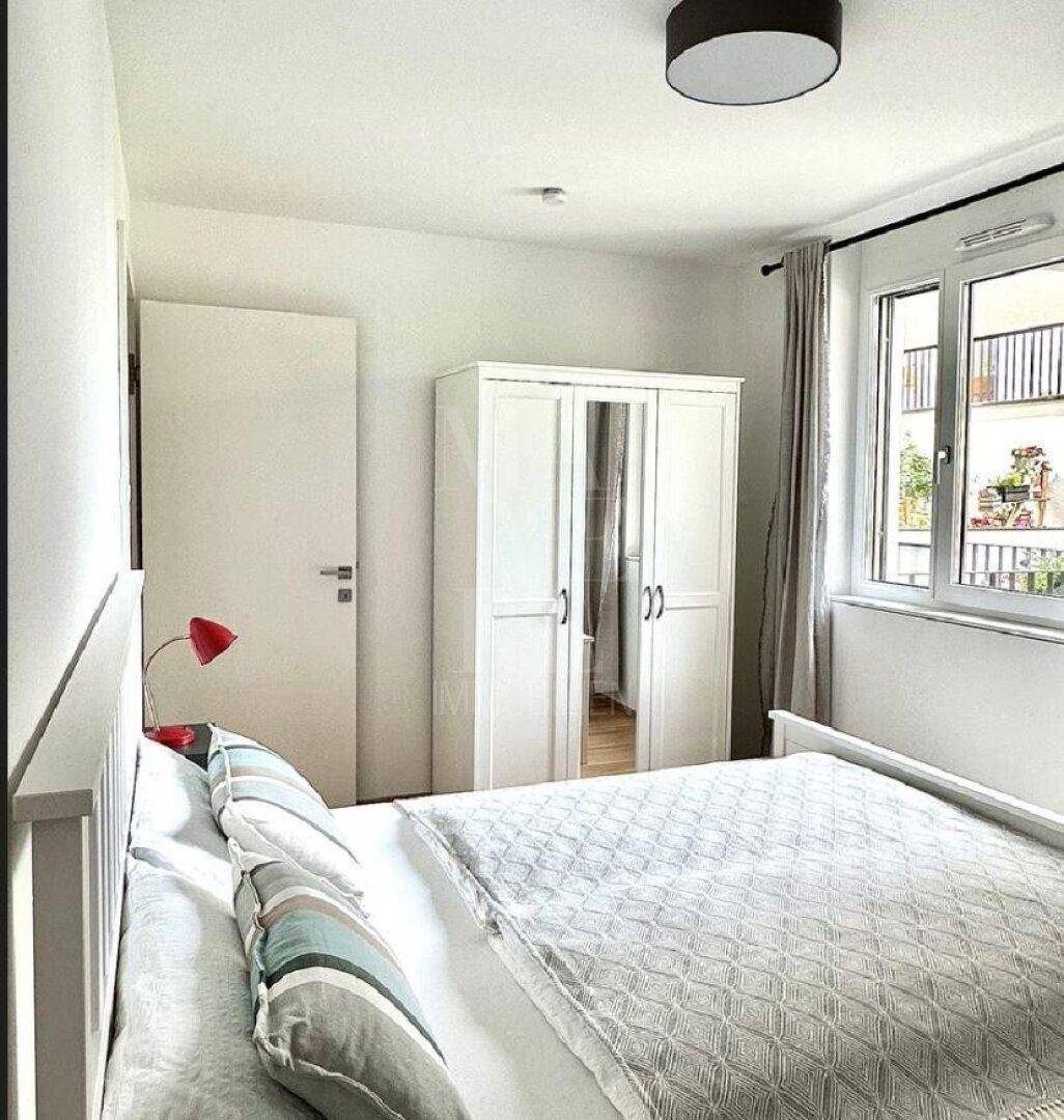 Schlafzimmer mit weißem Kleiderschrank, Holzboden und Fenster mit Blick auf den Außenbereich.