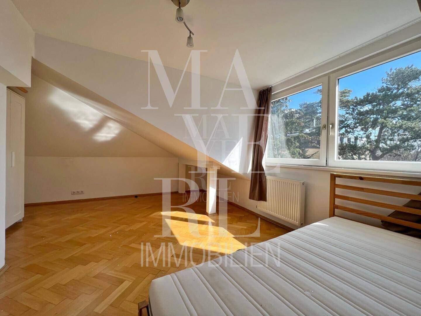 Schlafzimmer im Dachgeschoss mit Parkettboden, Dachschräge und großen Fenstern mit Weitblick.