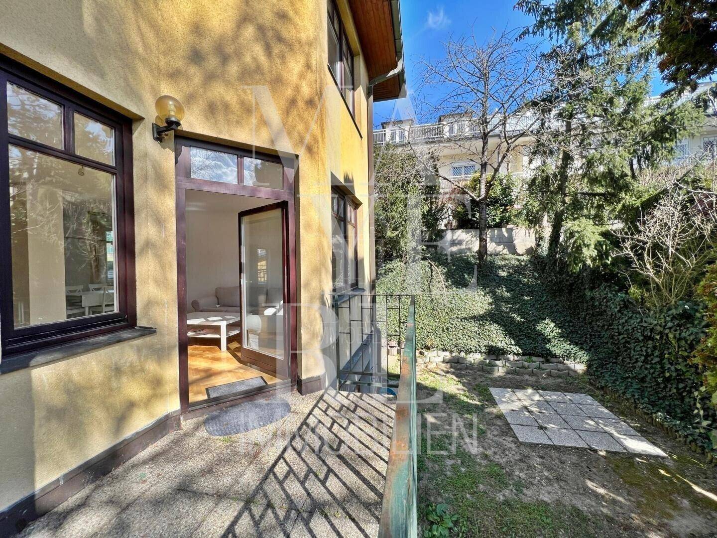 Kleine Terrasse am Haus mit Zugang zum Garten und Blick auf die grüne Umgebung.