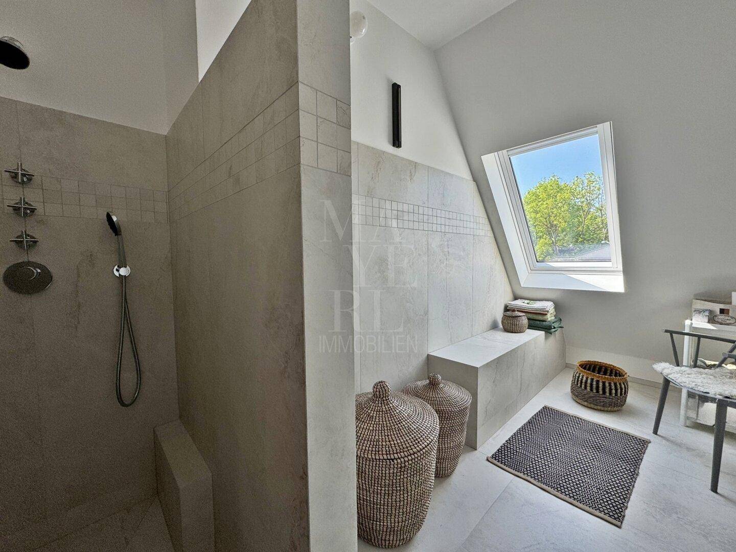 Modernes Badezimmer mit begehbarer Dusche, hellen Fliesen und Dachfenster für viel Tageslicht.