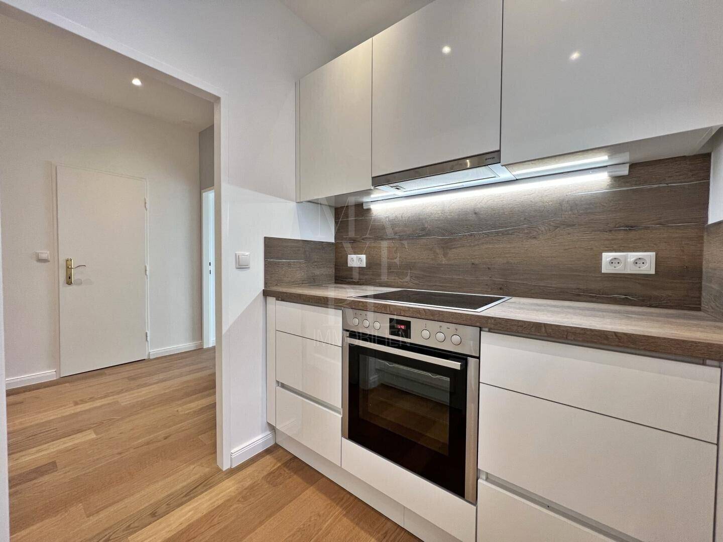 Moderne Einbauküche mit weißen Hochglanzschränken, integriertem Backofen und Induktionskochfeld.
