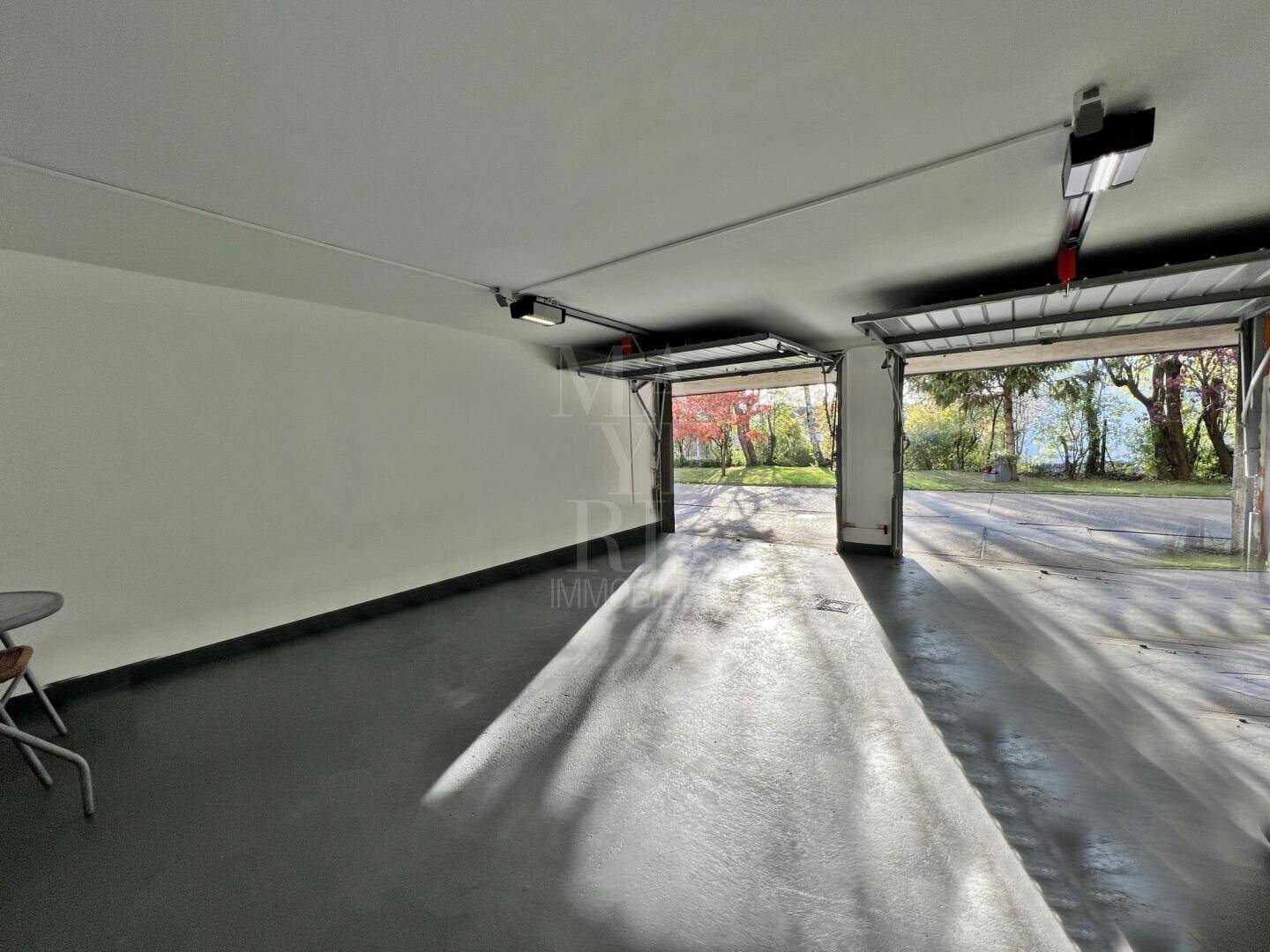 Geräumige Doppelgarage mit zwei geöffneten Toren und Blick ins Grüne.