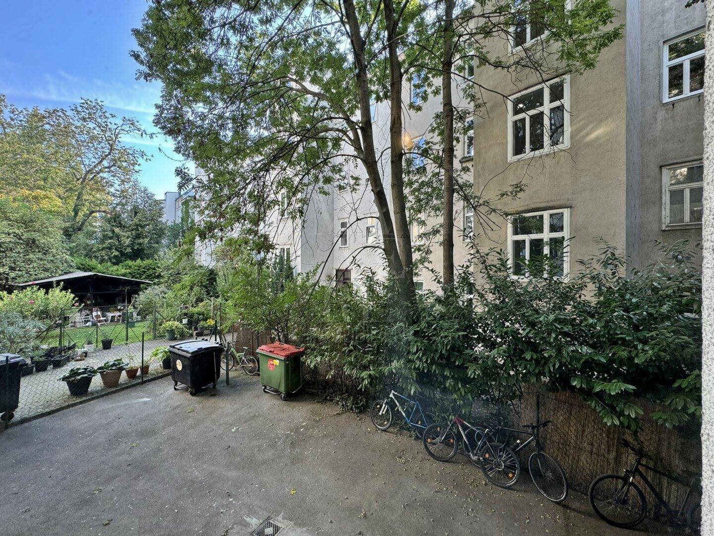 Grüner Innenhof mit Bäumen, Fahrradstellplätzen und Blick auf die umliegenden Gebäude.