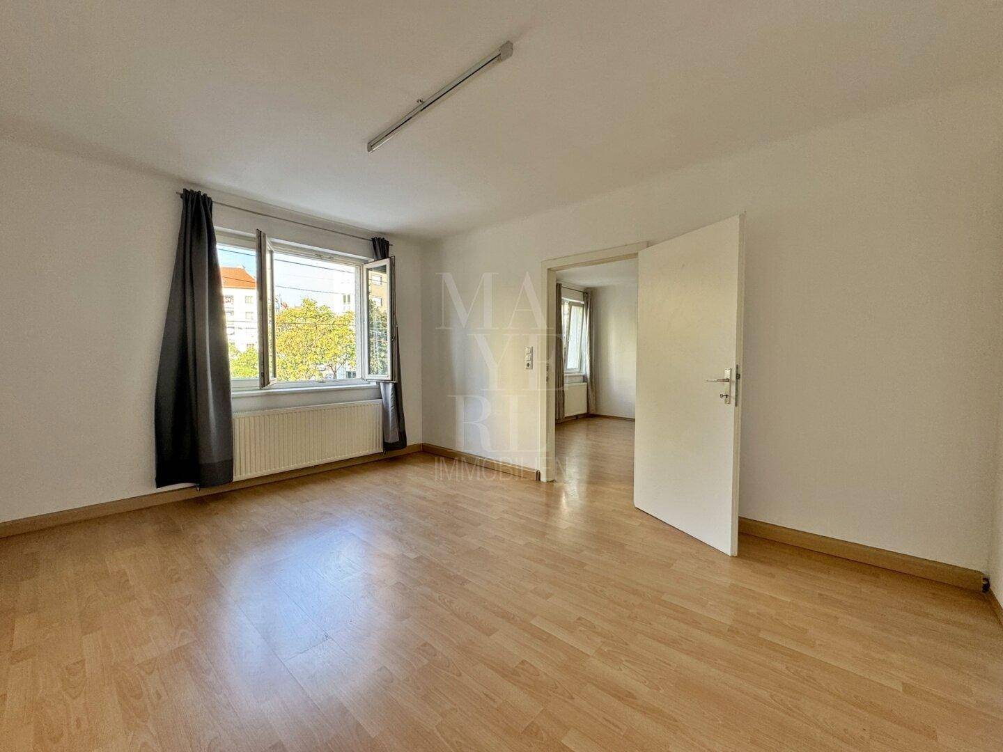 Lichtdurchfluteter Raum mit Laminatboden und Zugang zu weiteren Zimmern, vielseitig nutzbar.