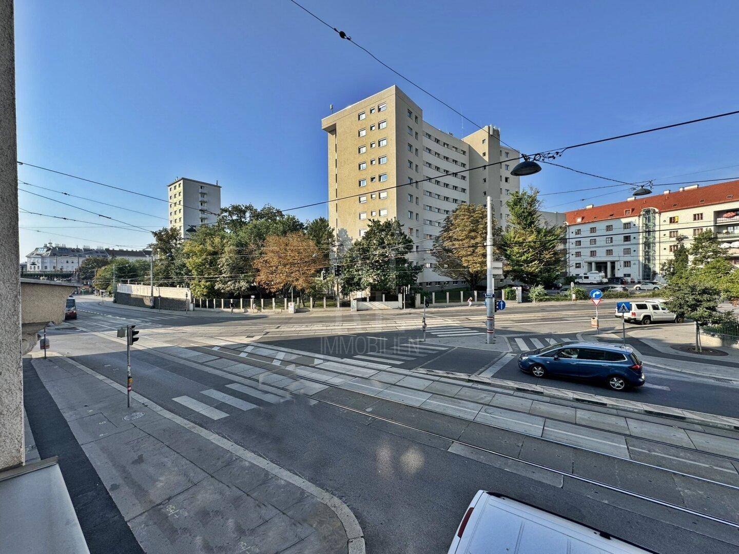 Weitläufige Straßenansicht mit städtischer Bebauung und Verkehr, unter blauem Himmel.