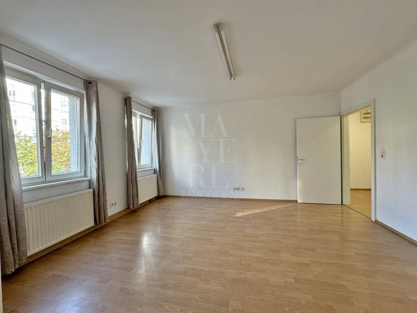 Geräumiges, helles Zimmer mit Laminatboden und Blick nach draußen, ideal als Wohnbereich.
