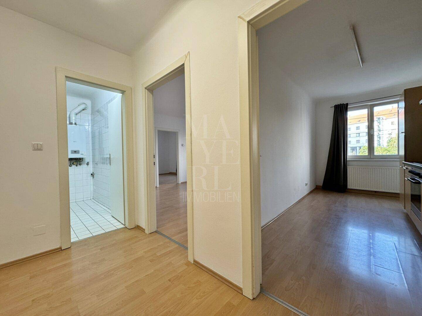 Heller Flur mit Laminatboden und Zugängen zu verschiedenen Räumen der Wohnung.