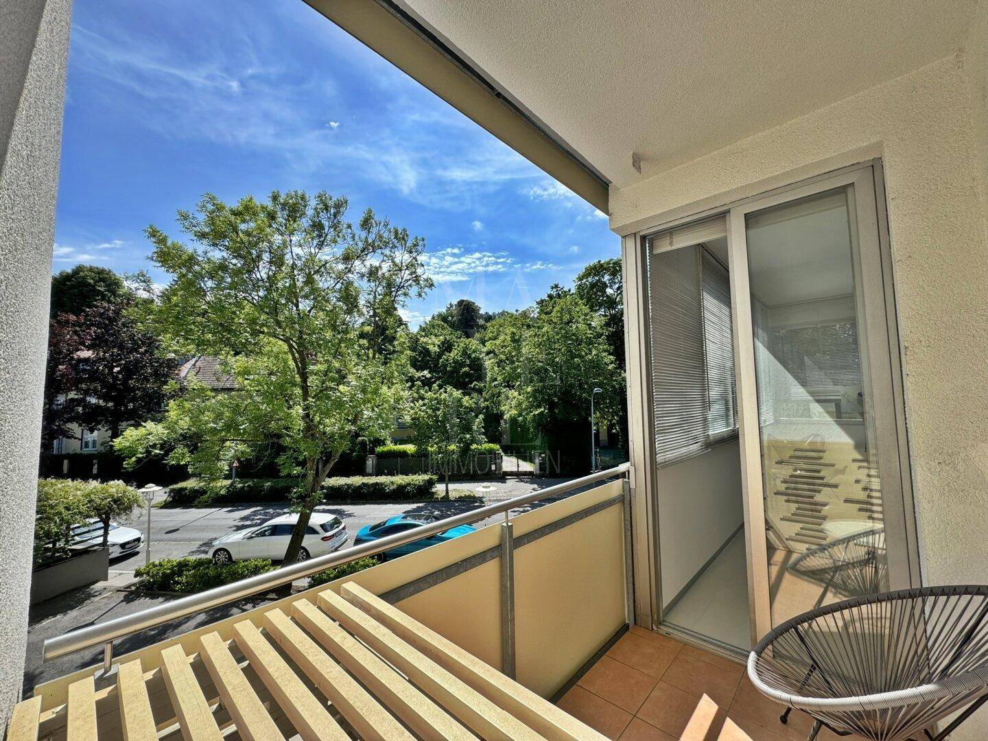 Sonniger Balkon mit Blick auf die grüne Umgebung und die Straße, ideal zum Entspannen.