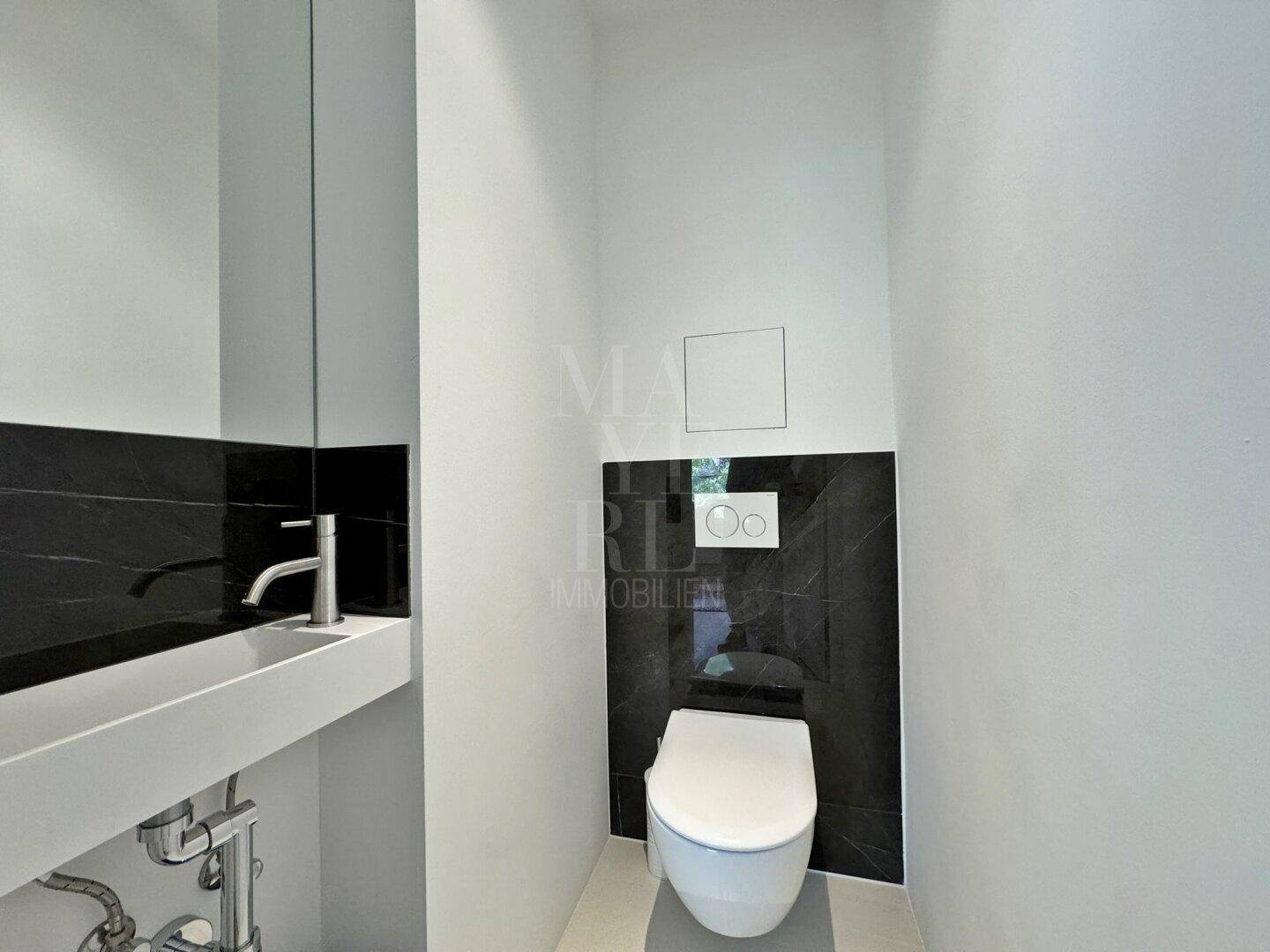 Modernes Gäste-WC mit wandhängender Toilette und kleinem Waschbecken, elegant in Schwarz und Weiß.