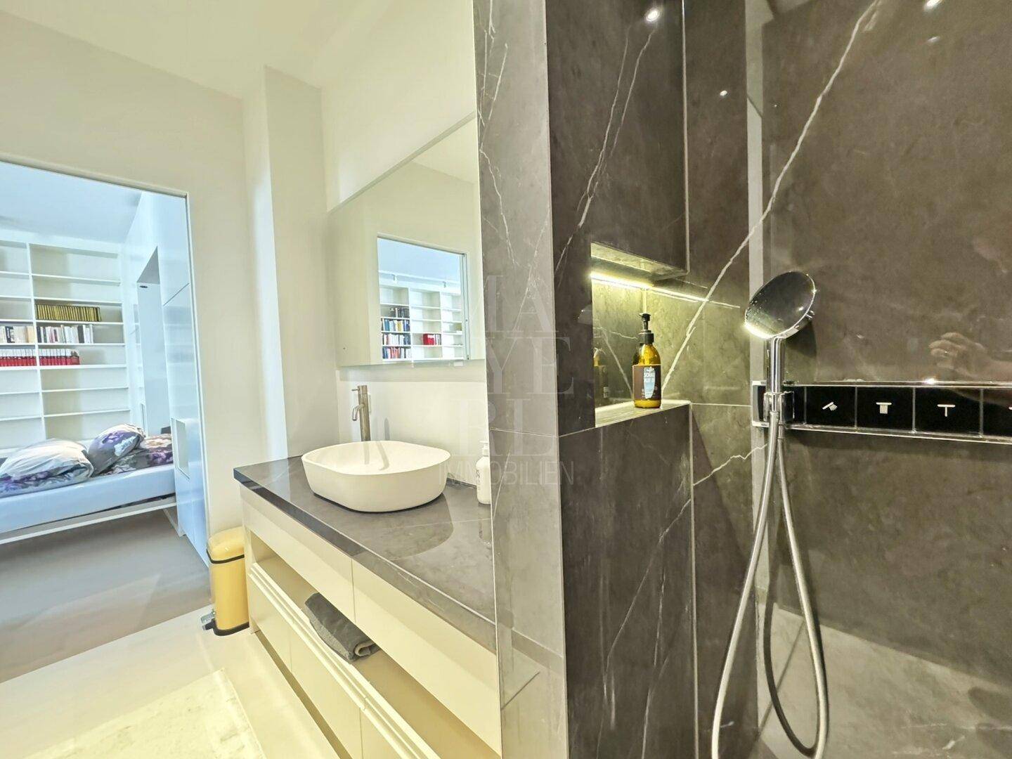 Modernes Badezimmer mit stilvollem Waschbecken, großem Spiegel und einer eleganten begehbaren Dusche.