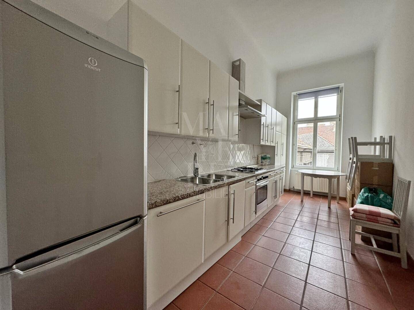 Funktionale Küche mit weißen Schränken, Granitarbeitsplatte und Terrakottafliesen.