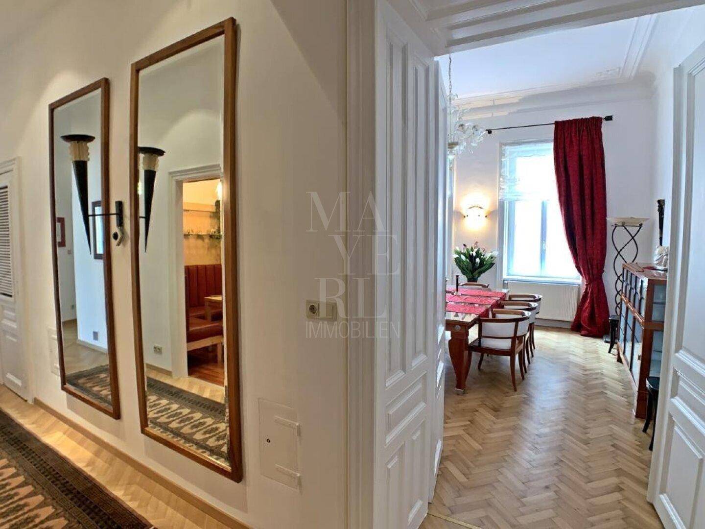 Heller Flur mit Parkettboden und großen Spiegeln, der zu weiteren Räumen führt.