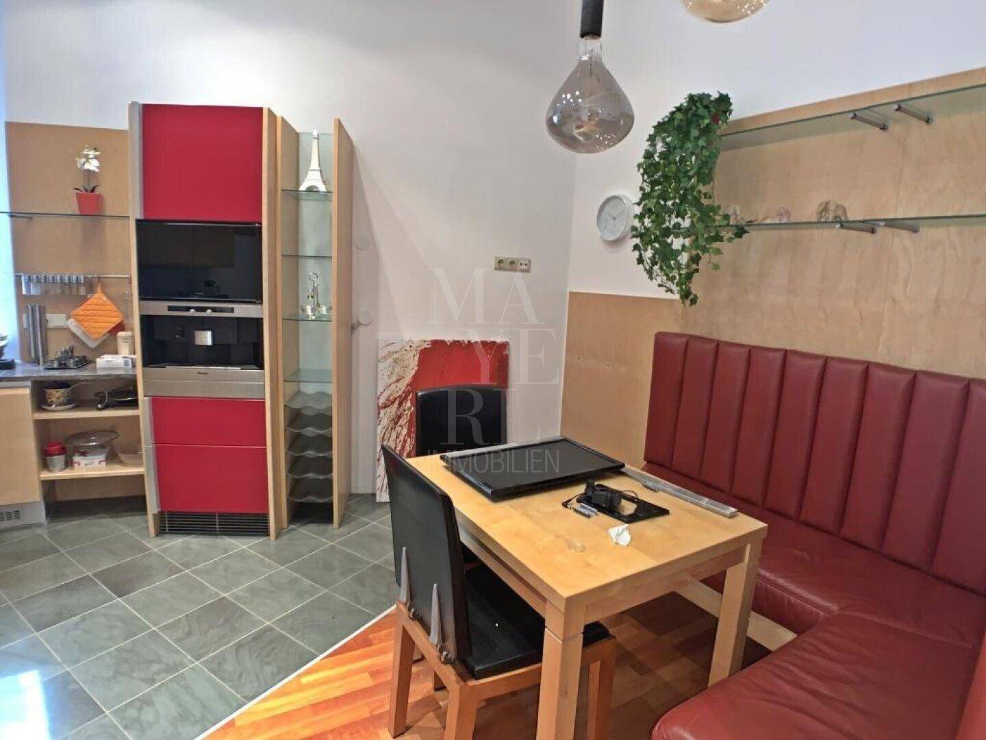 Gemütliche Küche mit Essecke, Holztisch und roter Sitzbank, ideal für Mahlzeiten.
