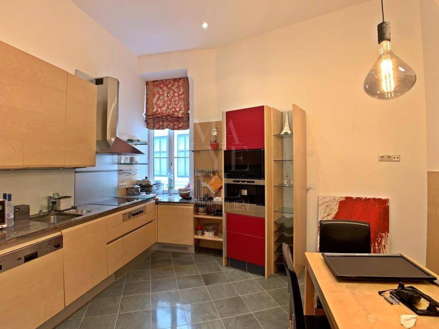 Moderne Küche mit Holzelementen, Fliesenboden und integrierten Geräten.