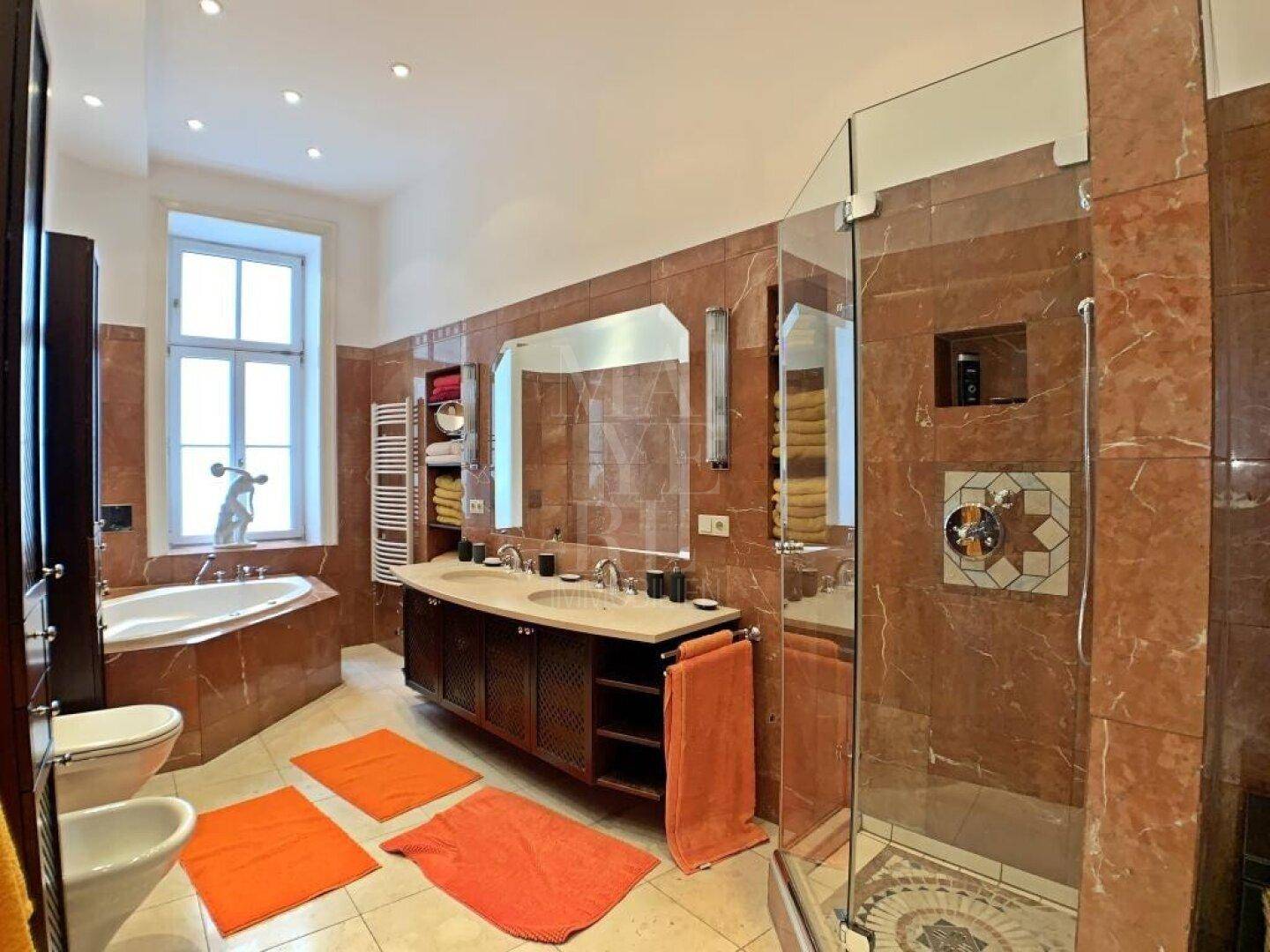 Luxuriöses Badezimmer mit Marmorfliesen, Doppelwaschbecken, Badewanne und großer Dusche.