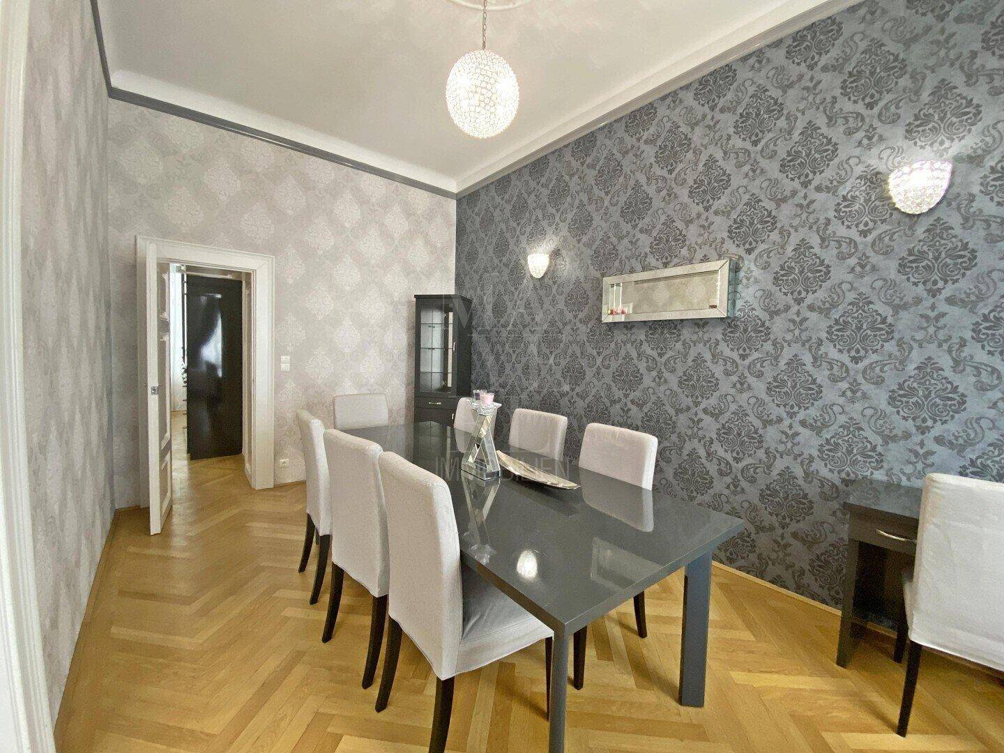 Eleganter Essbereich mit großem Tisch, modernen Stühlen und Fischgrätparkett.