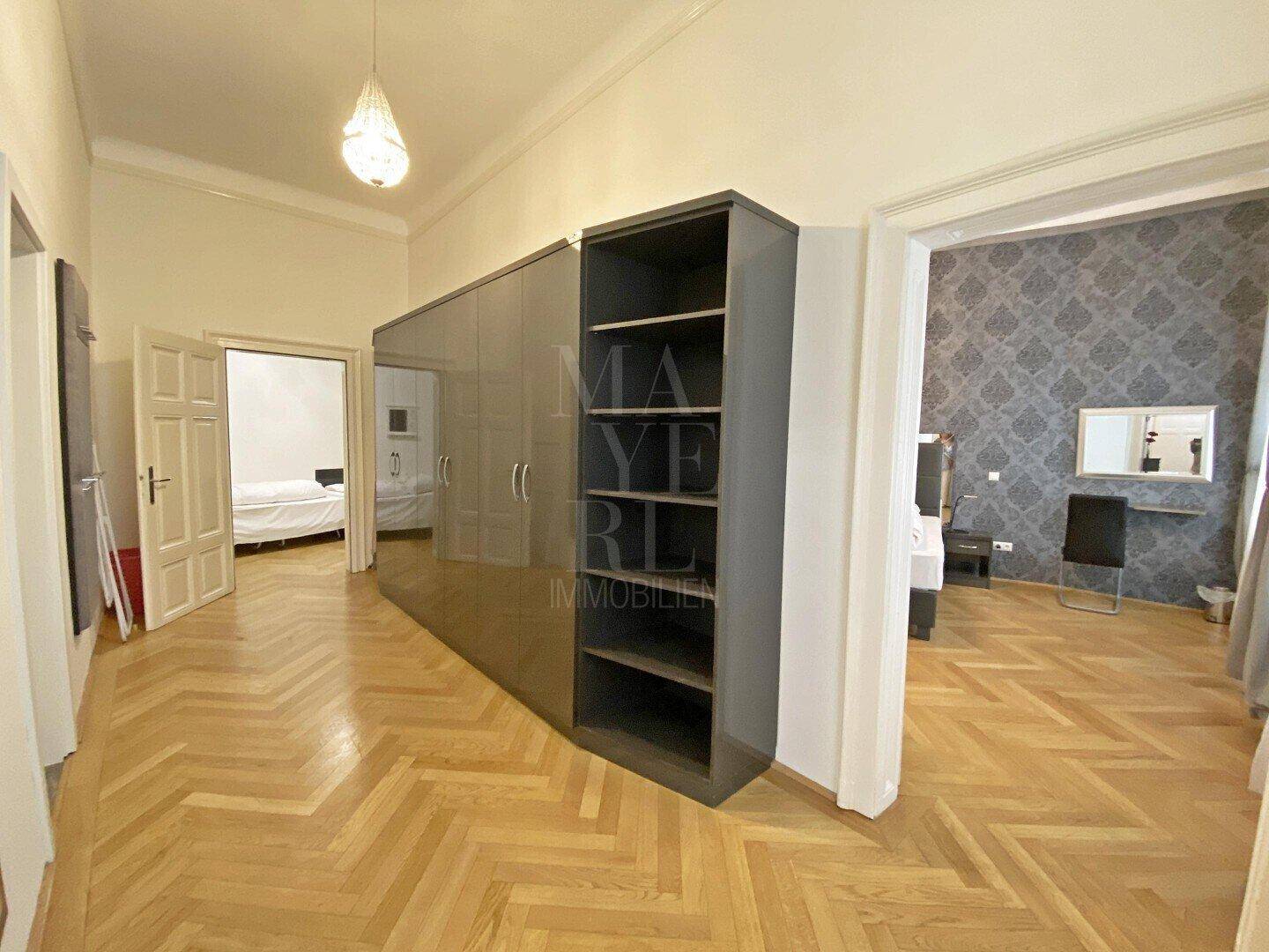 Geräumiger Flur mit Fischgrätparkett und großem, glänzendem Kleiderschrank.