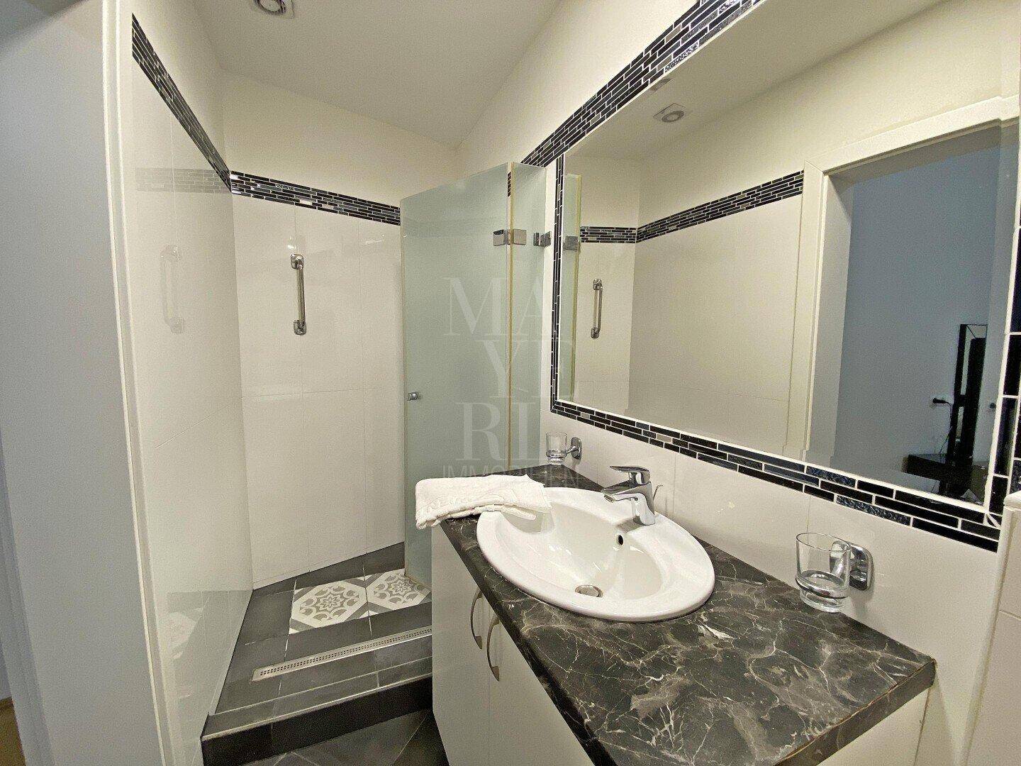 Modernes Badezimmer mit Dusche, Einzelwaschbecken und dekorativen Fliesen.
